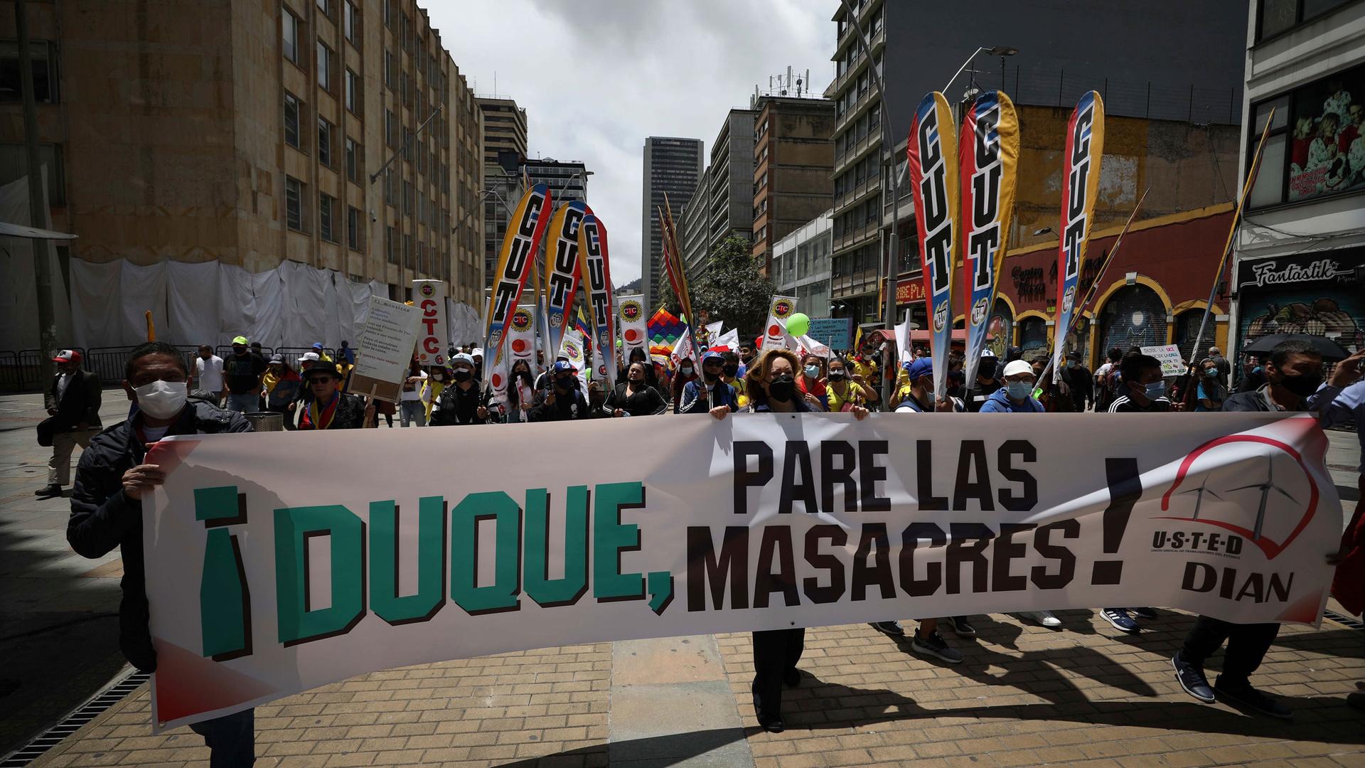 Protesters hold a banner with a message that reads in Spanish: "Duque, stop the massacres," directed at Colombia's President Ivan Duque, as they march to Bolivar Square in Bogotá, Colombia, Wednesday, May 12, 2021.