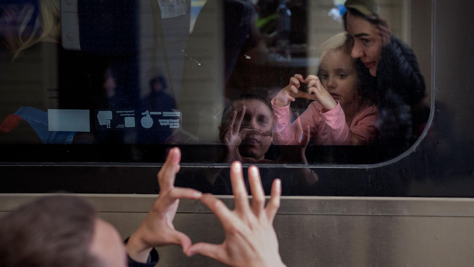 Ukrainian Nicolai, 41, says goodbye to his daughter Elina, 4, and his wife Lolita, on a train bound for Poland fleeing from the war at the train station in Lviv, western Ukraine, Friday, April 15, 2022.