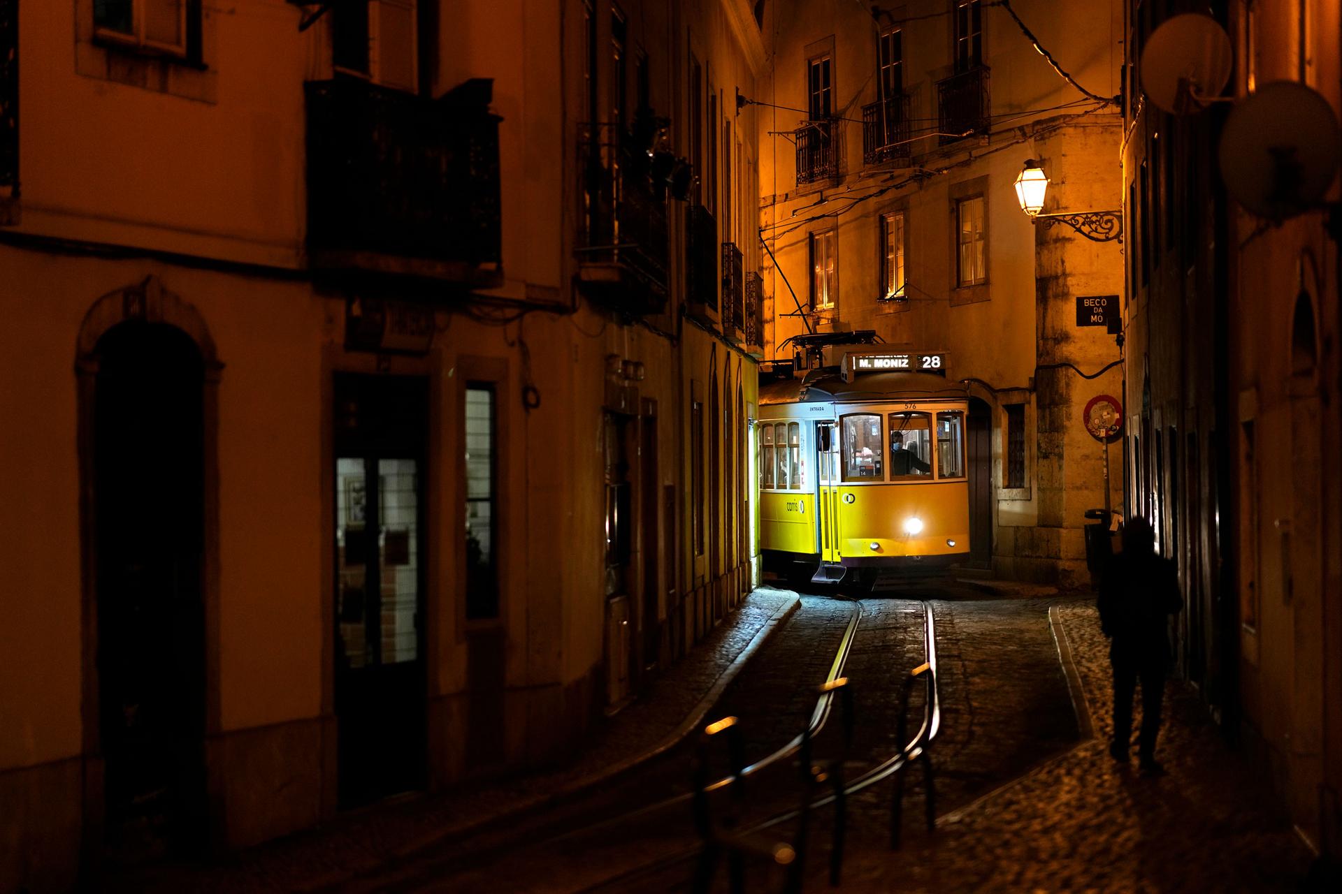 A number 28 tram drives through a narrow street in Lisbon's old Alfama neighborhood, Friday, Dec. 17, 2021.