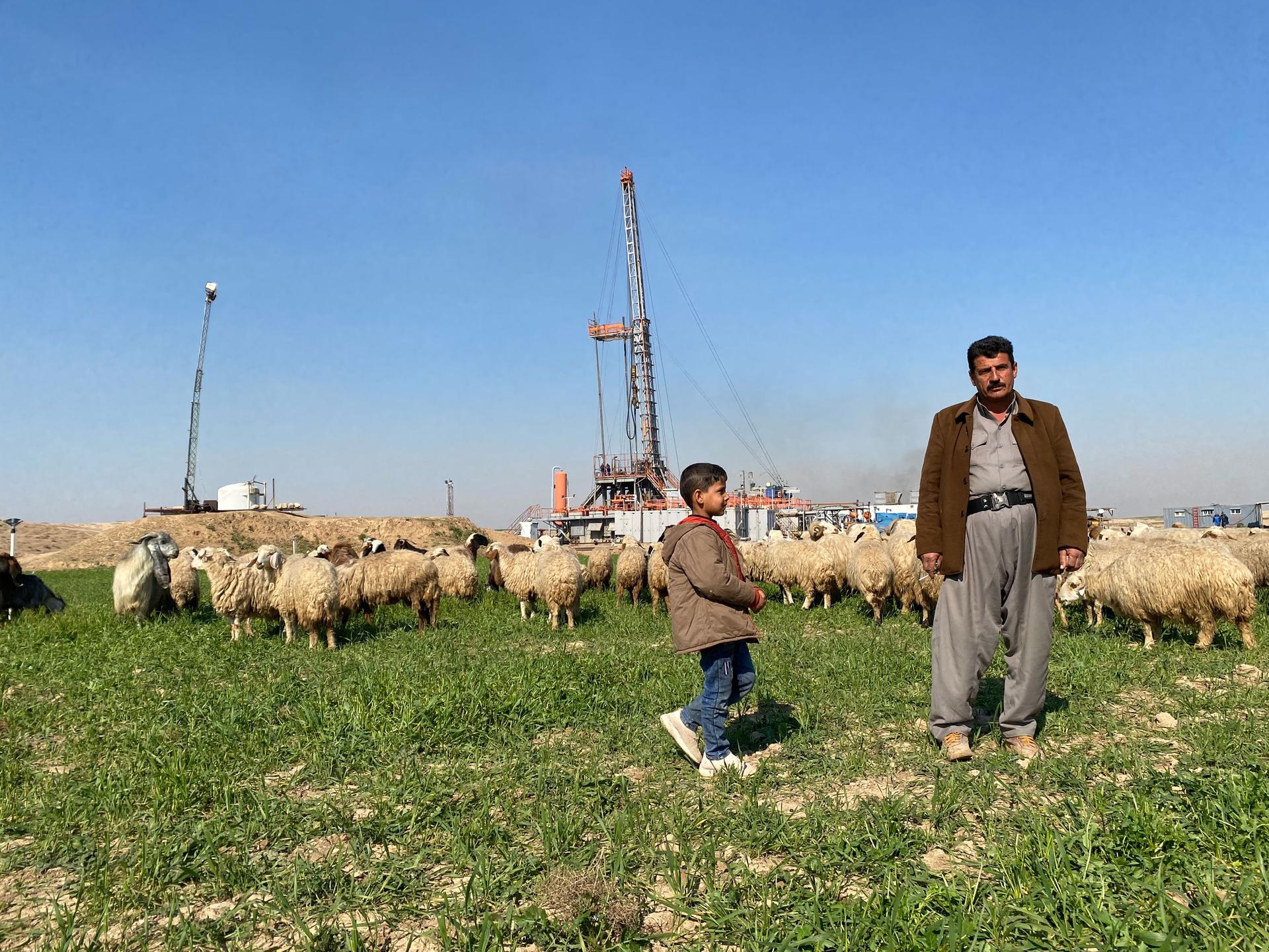 Hassan Mohammed Hassan, Lheiban village’s community leader, poses for a picture among sheep at his farm, with his 5-year-old son Mohammed, nicknamed Kako. The property borders a small oil field where Hassan works in security at night. 