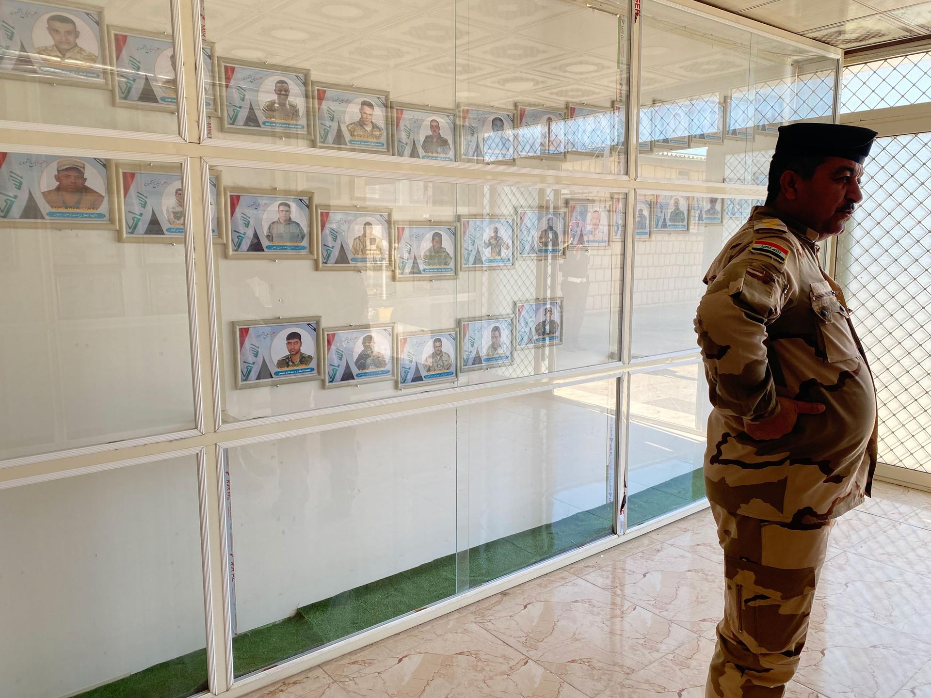 An Iraqi soldier at a base in Makhmour stands in front of framed pictures of armed forces killed in action.