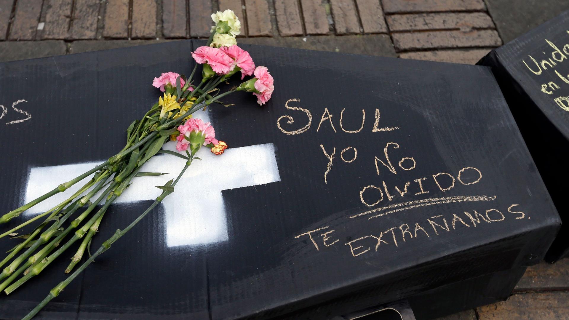 Flowers lay on a symbolic casket that represents a victims of Colombia's civil conflict, and carries the Spanish words: "Saul. I don't forget. We miss you," at Bolivar square in Bogotá, Colombia, Monday, April 9, 2018. 