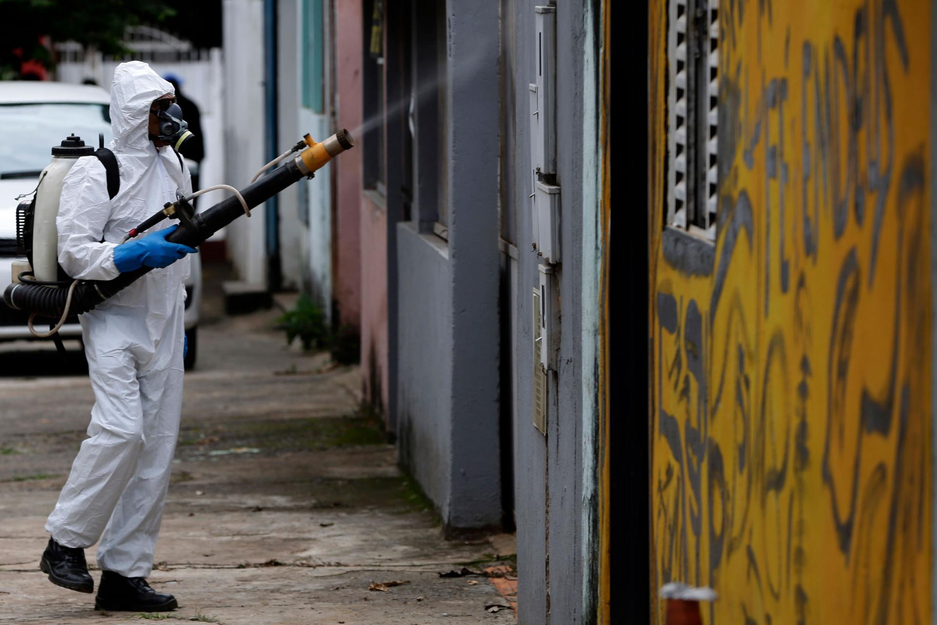 A government worker sprays insecticide outside homes on the outskirts of Brasilia, Brazil, Tuesday, Nov. 24, 2020. 