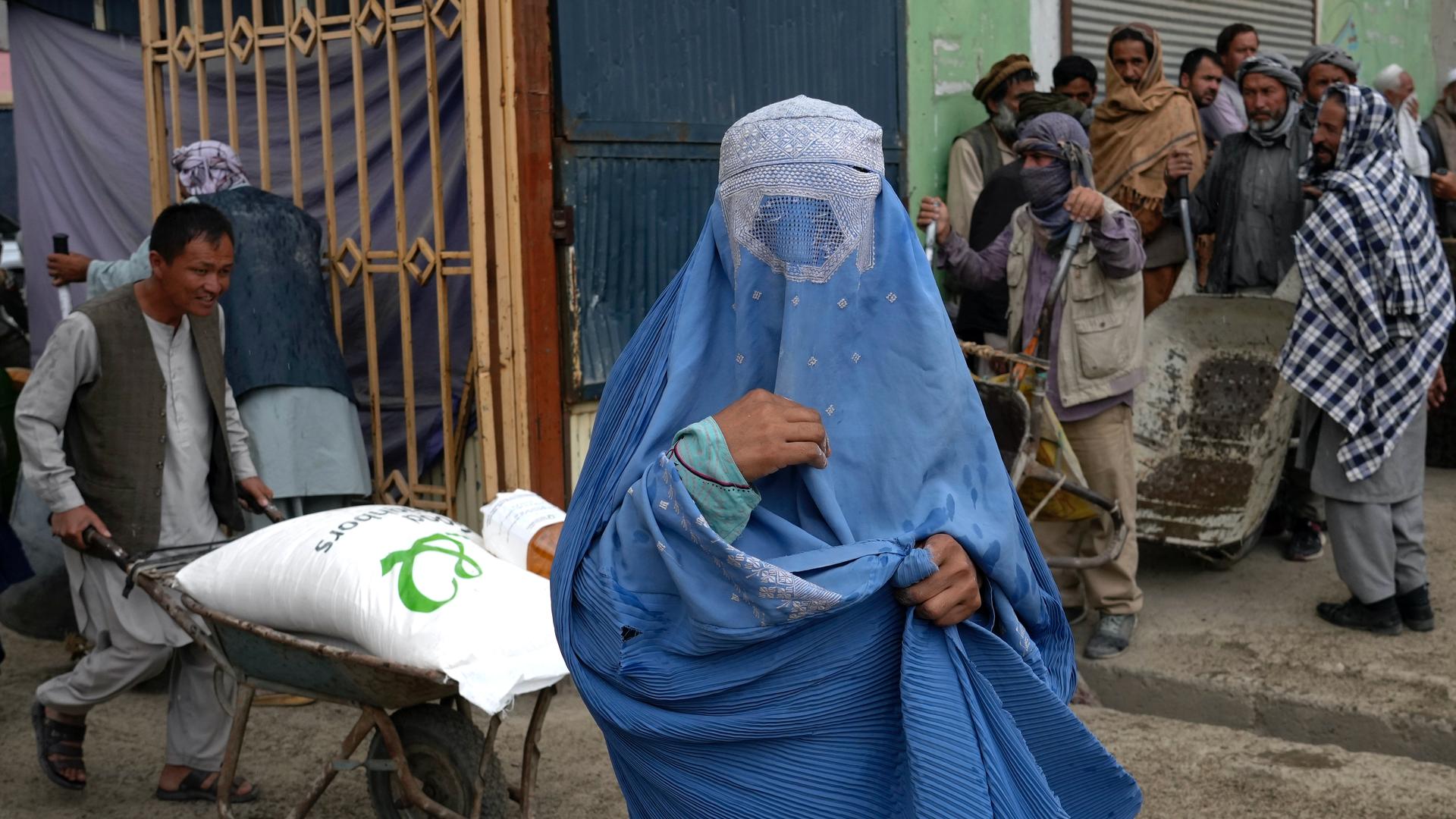 An Afghan woman waits to receive a food ration distributed by a South Korea humanitarian aid group, in Kabul, Afghanistan, May 10, 2022. 