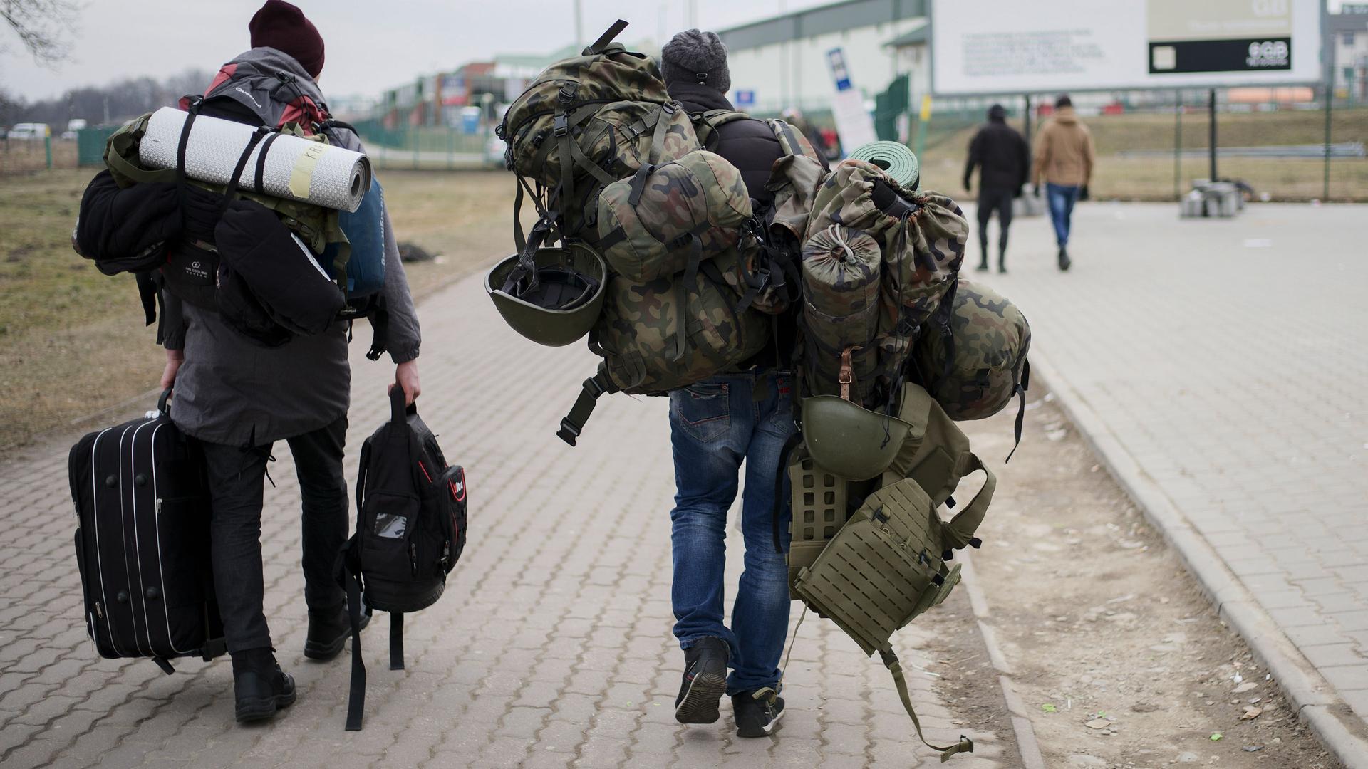 A man carries combat gear as he leaves Poland to fight in Ukraine, at the border crossing in Medyka, Poland, Wednesday, March 2, 2022. 