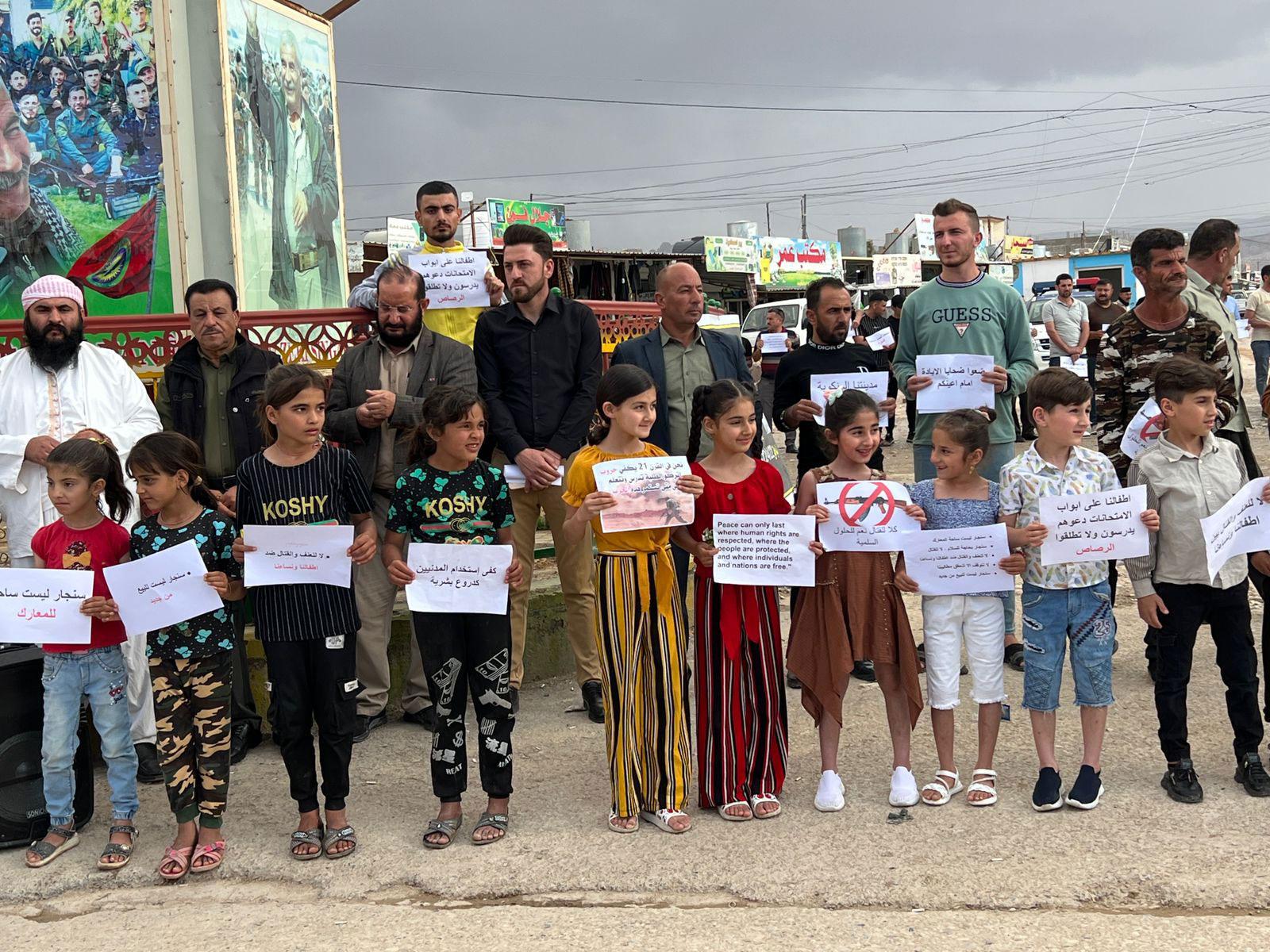 Adults and children in Sinjar protest and hold signs, calling on all armed groups to leave the area. The demonstrations come after recent fighting between the Iraqi army and a local militia.