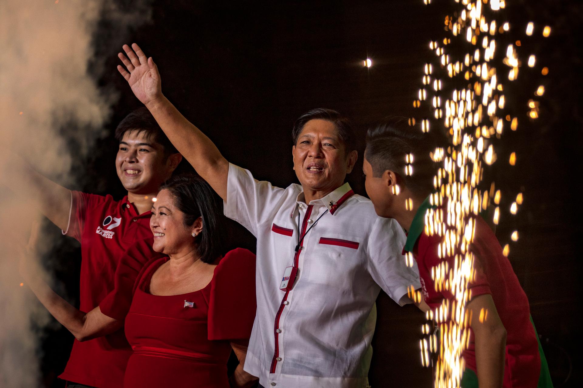 Bongbong Marcos holds up his hand in a celebratory pose as his wife and children look on