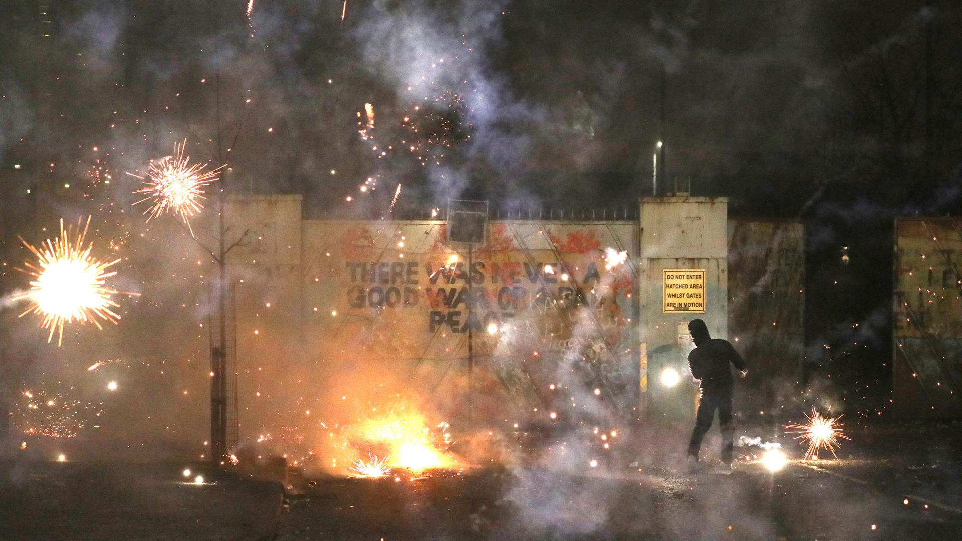 In this Wednesday, April 7, 2021 file photo, a firework explodes as Nationalist and Loyalist rioters clash with one another at the peace wall on Lanark Way in West Belfast, Northern Ireland.