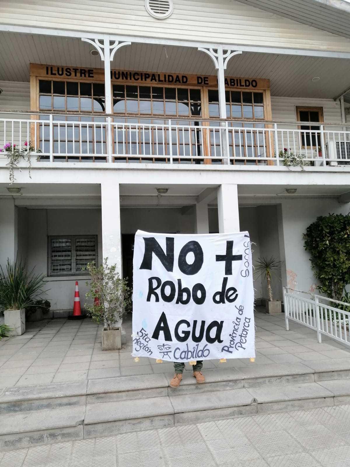 A person holding a sign that reads, “No more water robbery