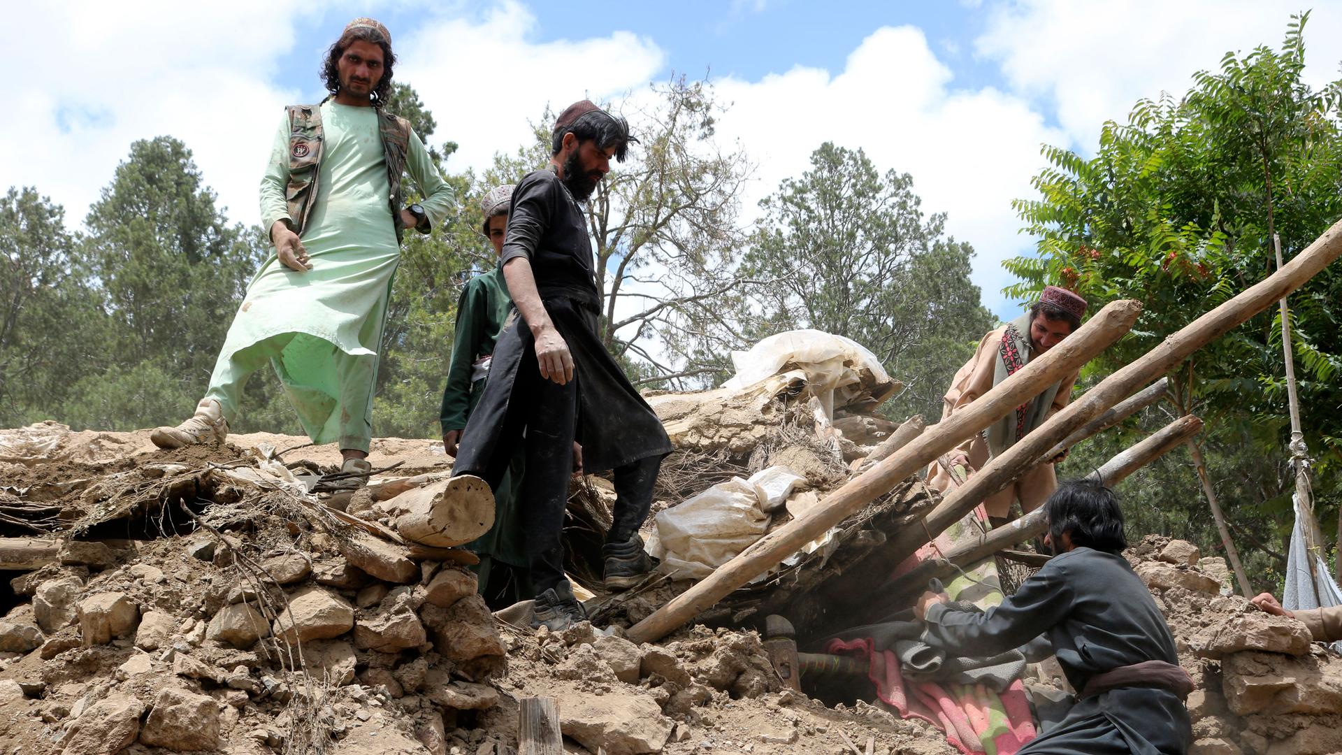 Afghan villagers collects belongings from under the rubble of a home that was destroyed in an earthquake in the Spera District of the southwestern part of Khost Province, Afghanistan, Wednesday, June 22, 2022. 