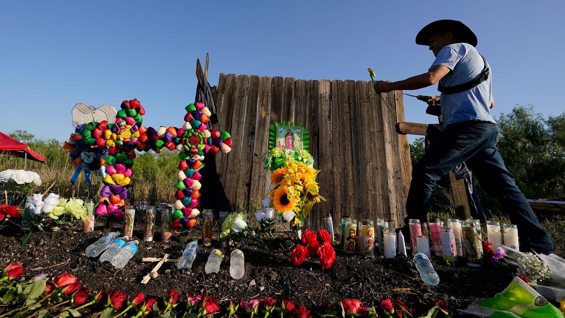 Roberto Marquez of Dallas adds a flower a makeshift memorial at the site where officials found dozens of people dead in an abandoned semitrailer containing suspected migrants, Wednesday, June 29, 2022, in San Antonio. 