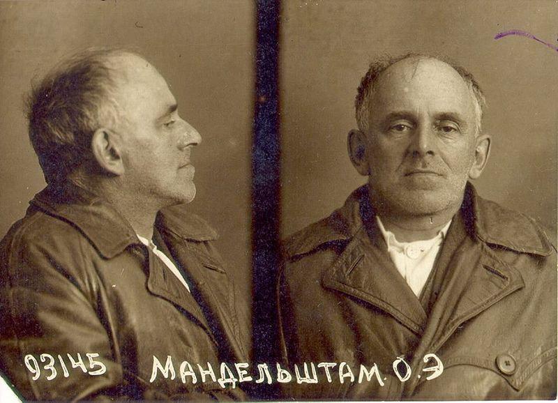 Antique black-and-white photo of prisoner, in profile and full face, with his name and prisoner number written on the photo in cyrillic