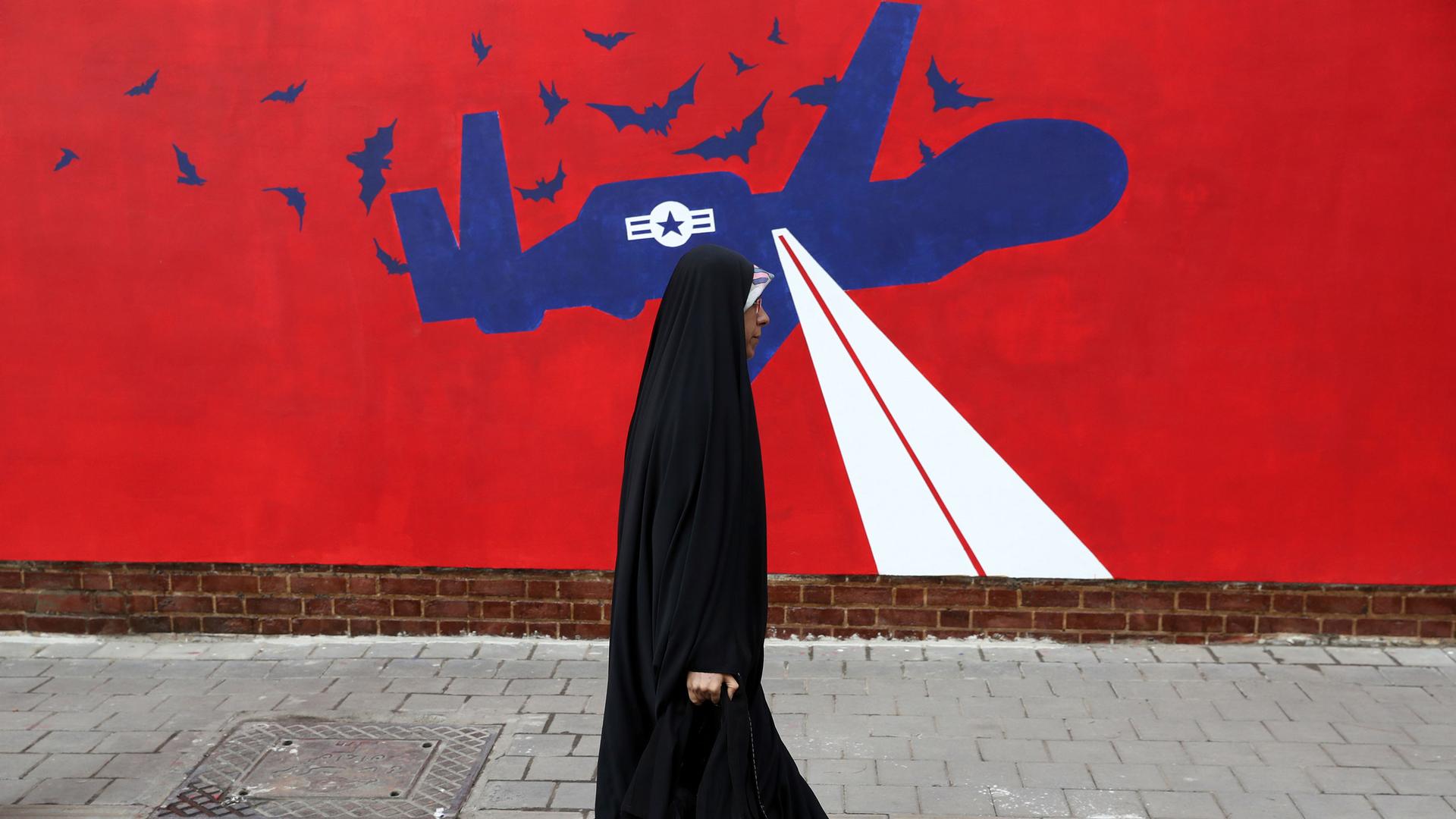 A woman walks past a new anti-US mural on the wall of former US Embassy portraying the interception of Global Hawk US drone by Iran in Persian Gulf, after an unveiling ceremony in Tehran, Iran, Saturday, Nov. 2, 2019. 