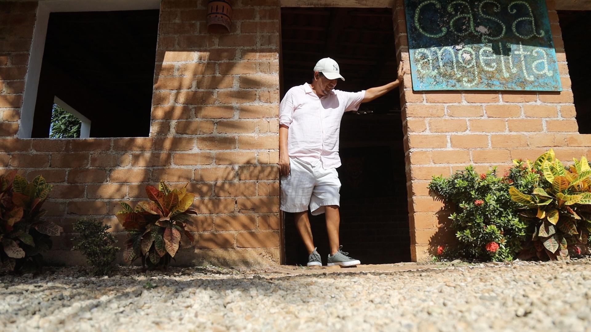 Omar Vazquez Sanchez stands in the doorway of a home built from blocks made of seaweed. 