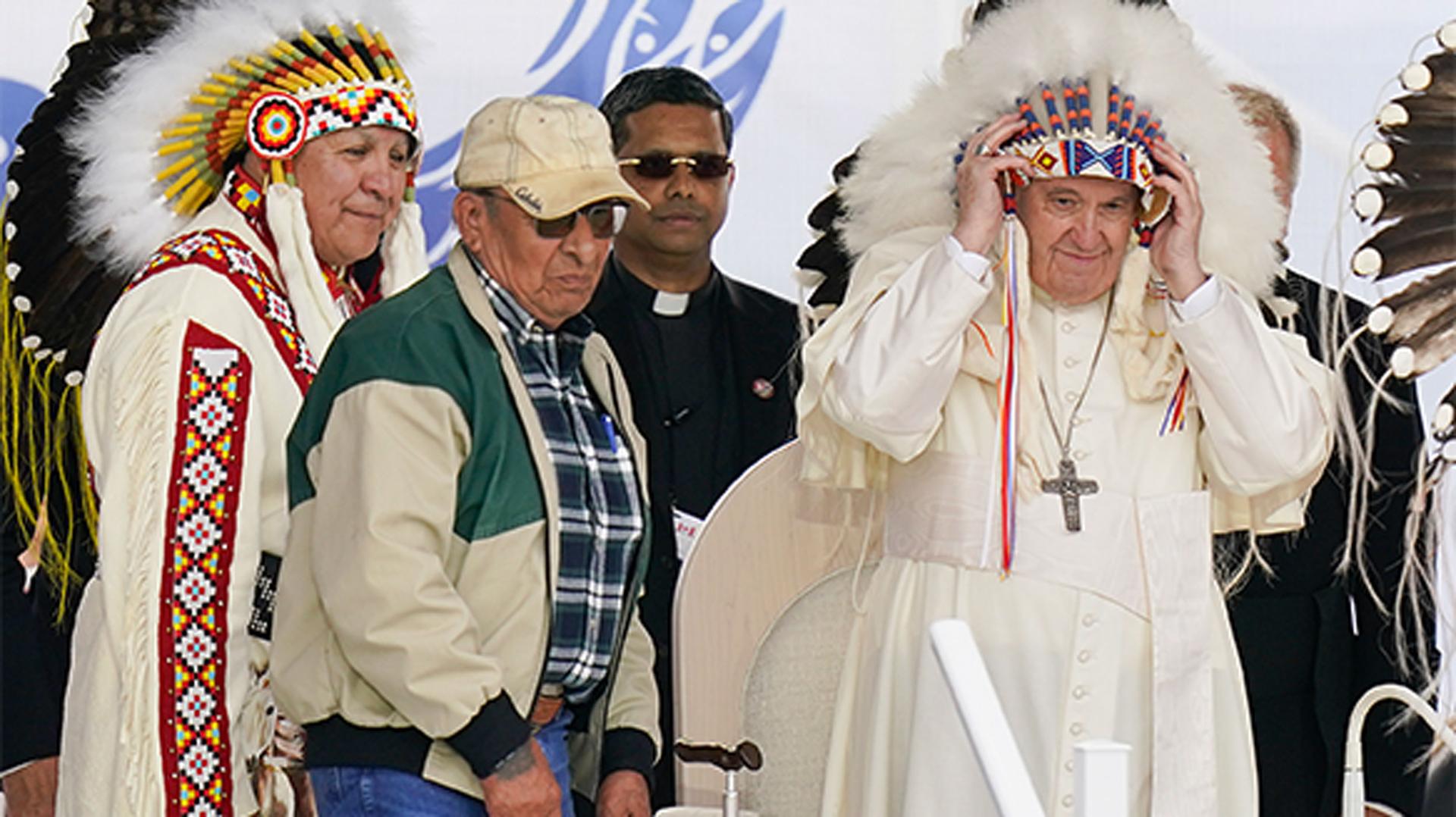Pope Francis dons a headdress during a visit with Indigenous peoples at Maskwaci, the former Ermineskin Residential School, in Maskwacis, Alberta, Canada