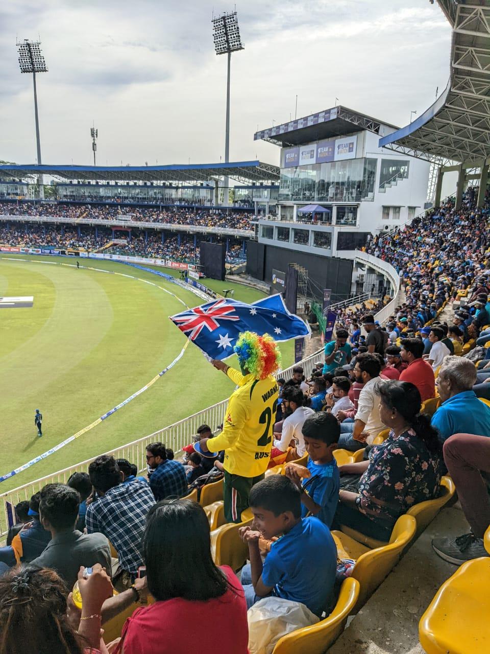 A Sri Lankan cricket fan wears yellow representing the rival Australian team and waves an Australian flag