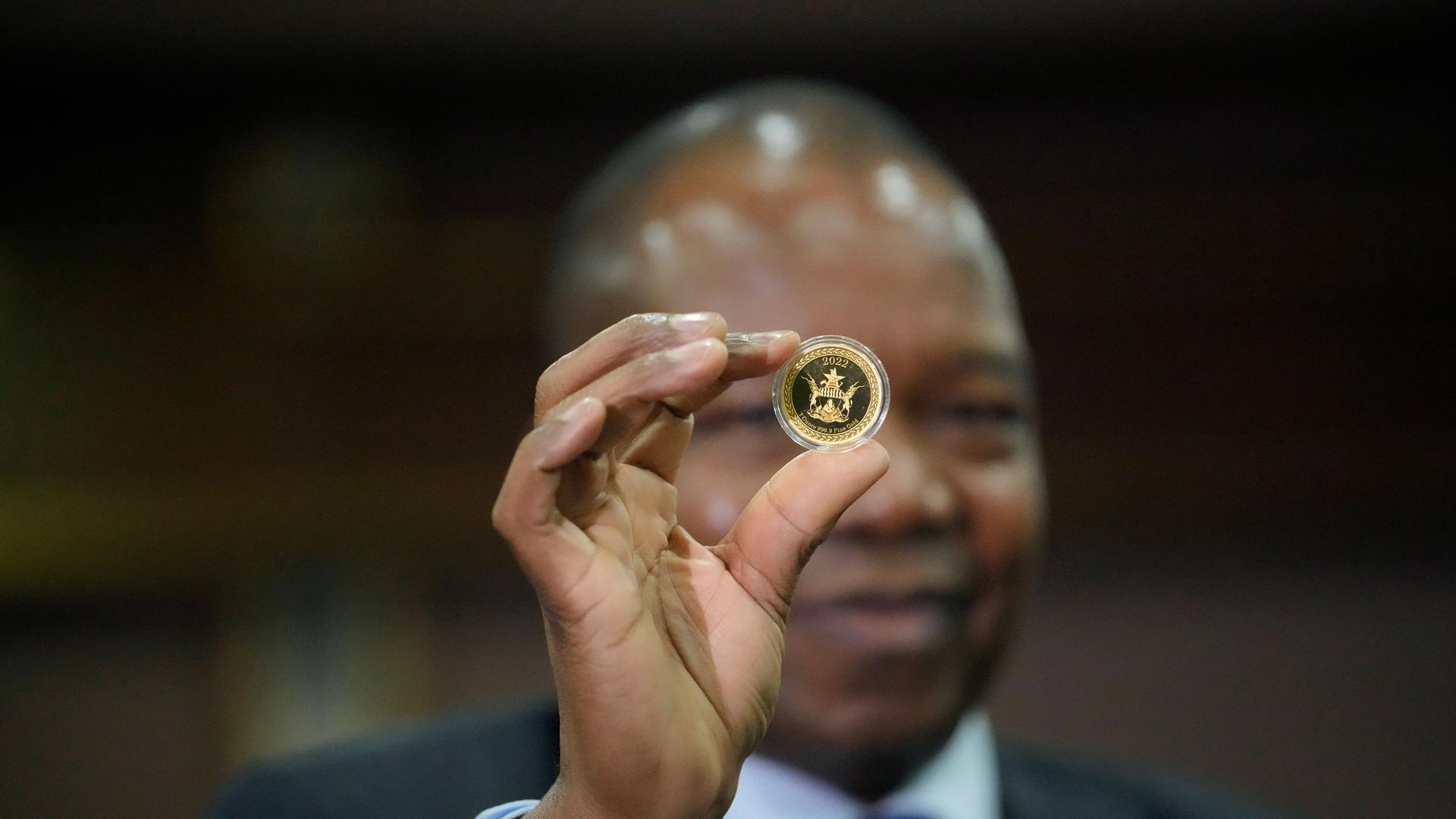 Reserve Bank of Zimbabwe Governor John Mangudya holds a sample of a gold coin at the launch in Harare, Monday, July, 25, 2022.