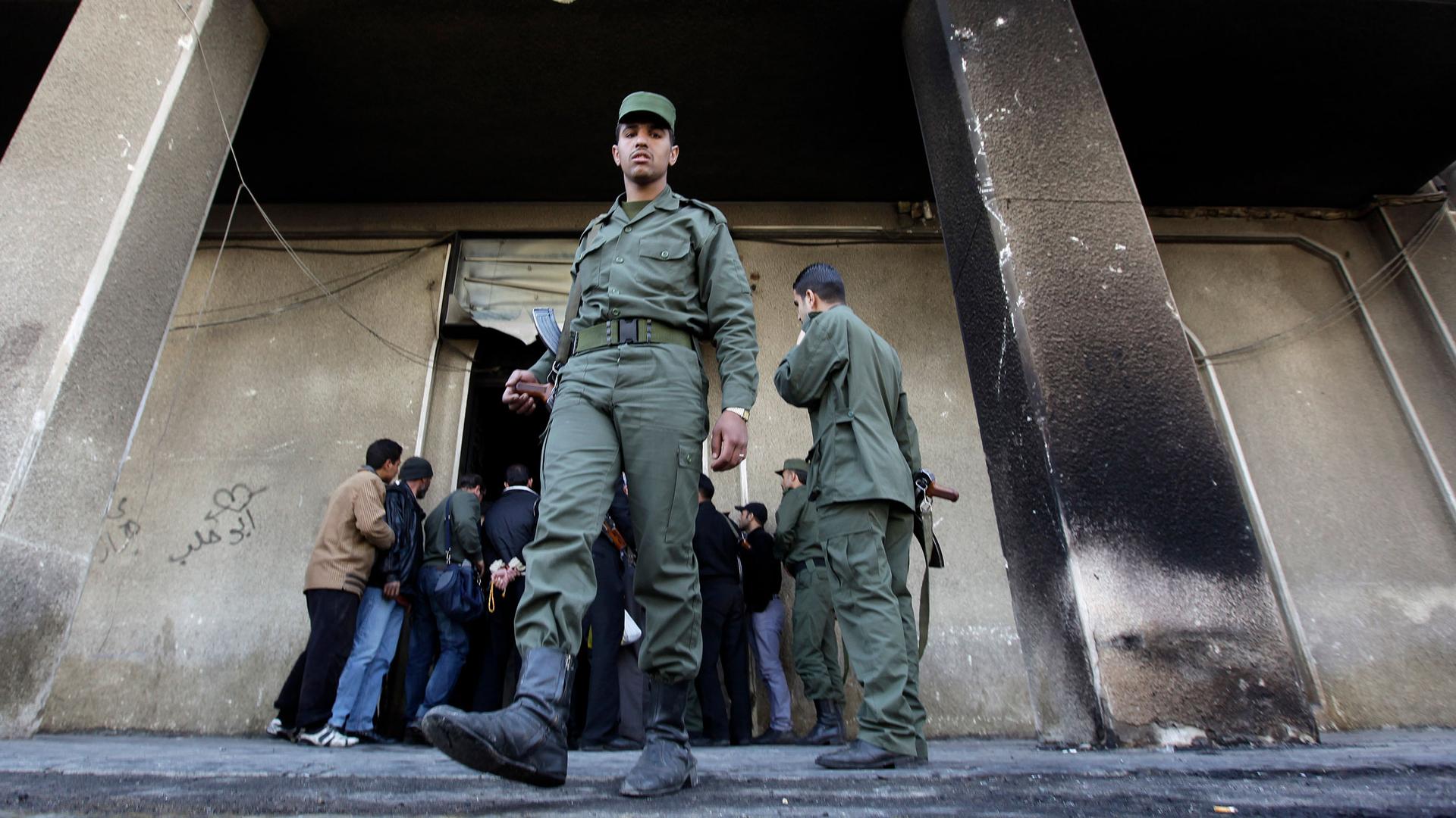 In this March 21, 2011, file photo, a Syrian soldier steps out of the burned courthouse that was set on fire by anti-government protesters in the southern city of Daraa, Syria. 