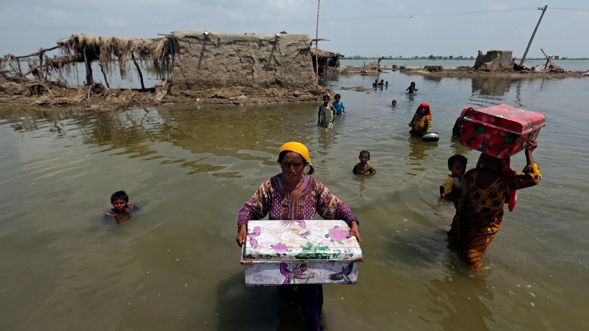 Women carry belongings salvaged from their flooded home after monsoon rains, in the Qambar Shahdadkot district of Sindh Province, of Pakistan, Tuesday, Sept. 6, 2022. 