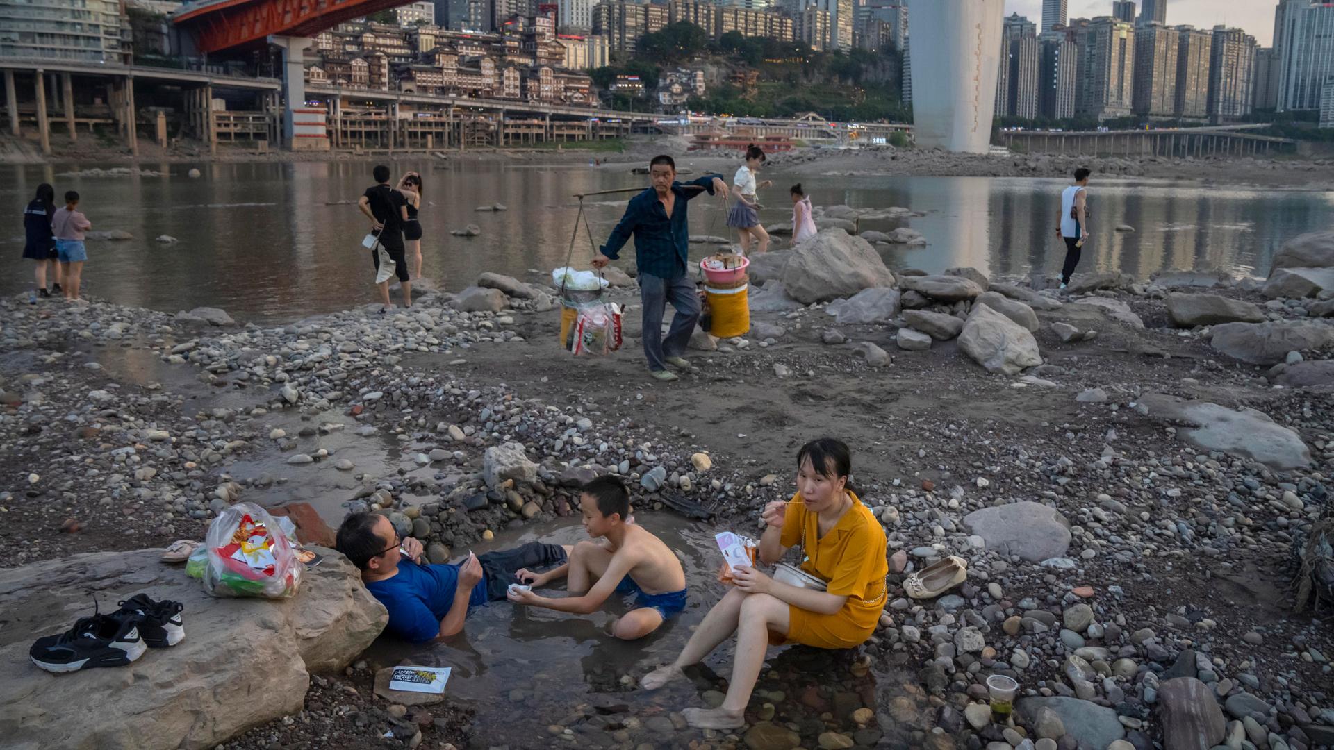 People sit in a shallow pool of water in the riverbed of the Jialing River, a tributary of the Yangtze, in southwestern China's Chongqing Municipality, Saturday, Aug. 20, 2022. 