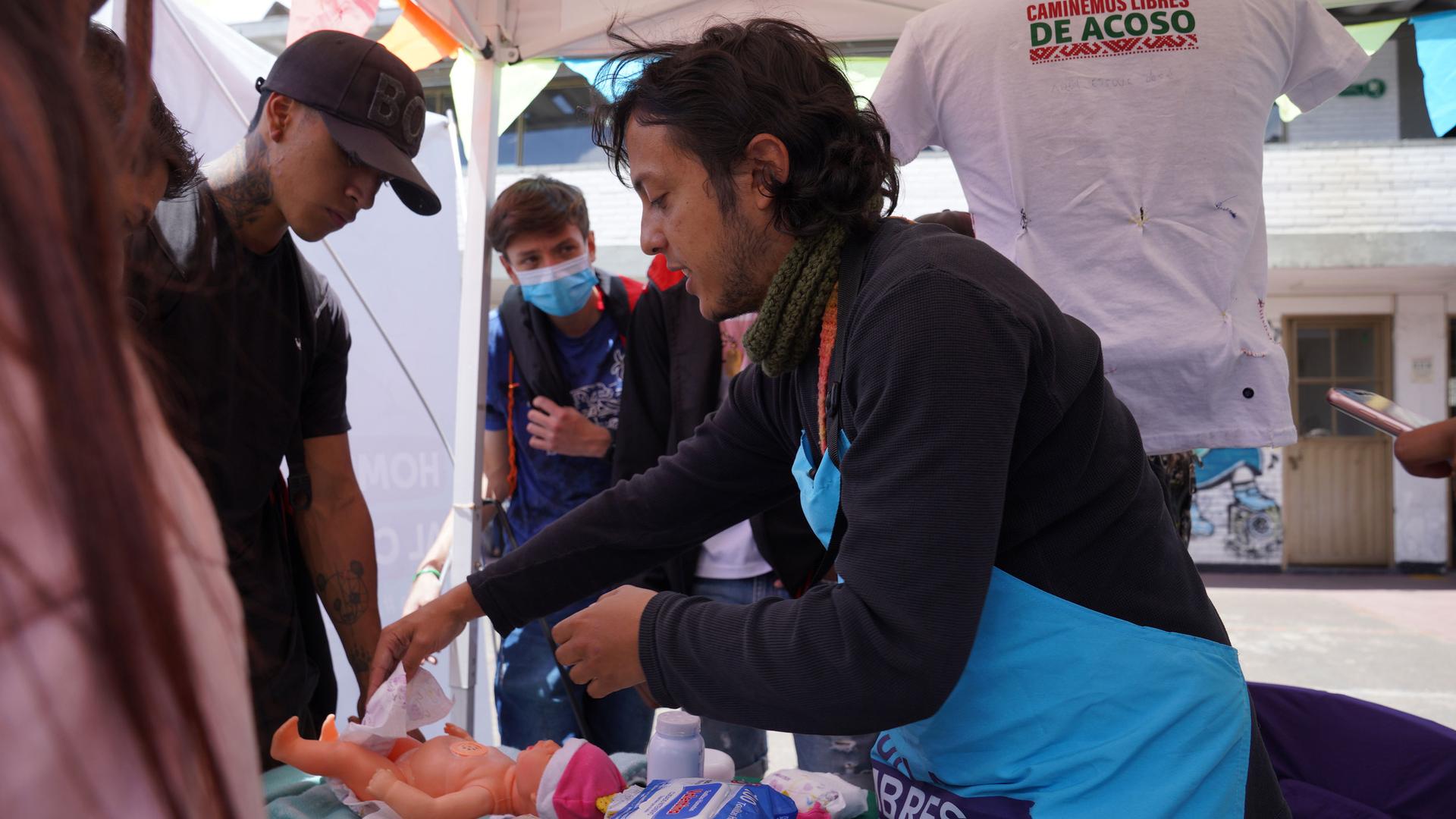 At a job fair in Bogotá, psychologist Nicolas Londoño showed groups of young men how to change a baby's diapers.  Londoño works with Care School for Men, an educational program funded by the city government. 