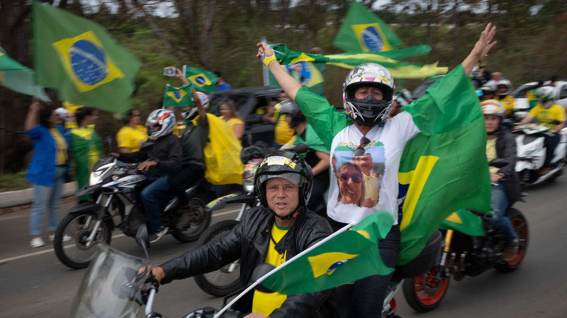 Supporters of Brazilian President Jair Bolsonaro wave Brazilian flags during a motorcycle campaign rally in Pocos de Caldas, Brazil