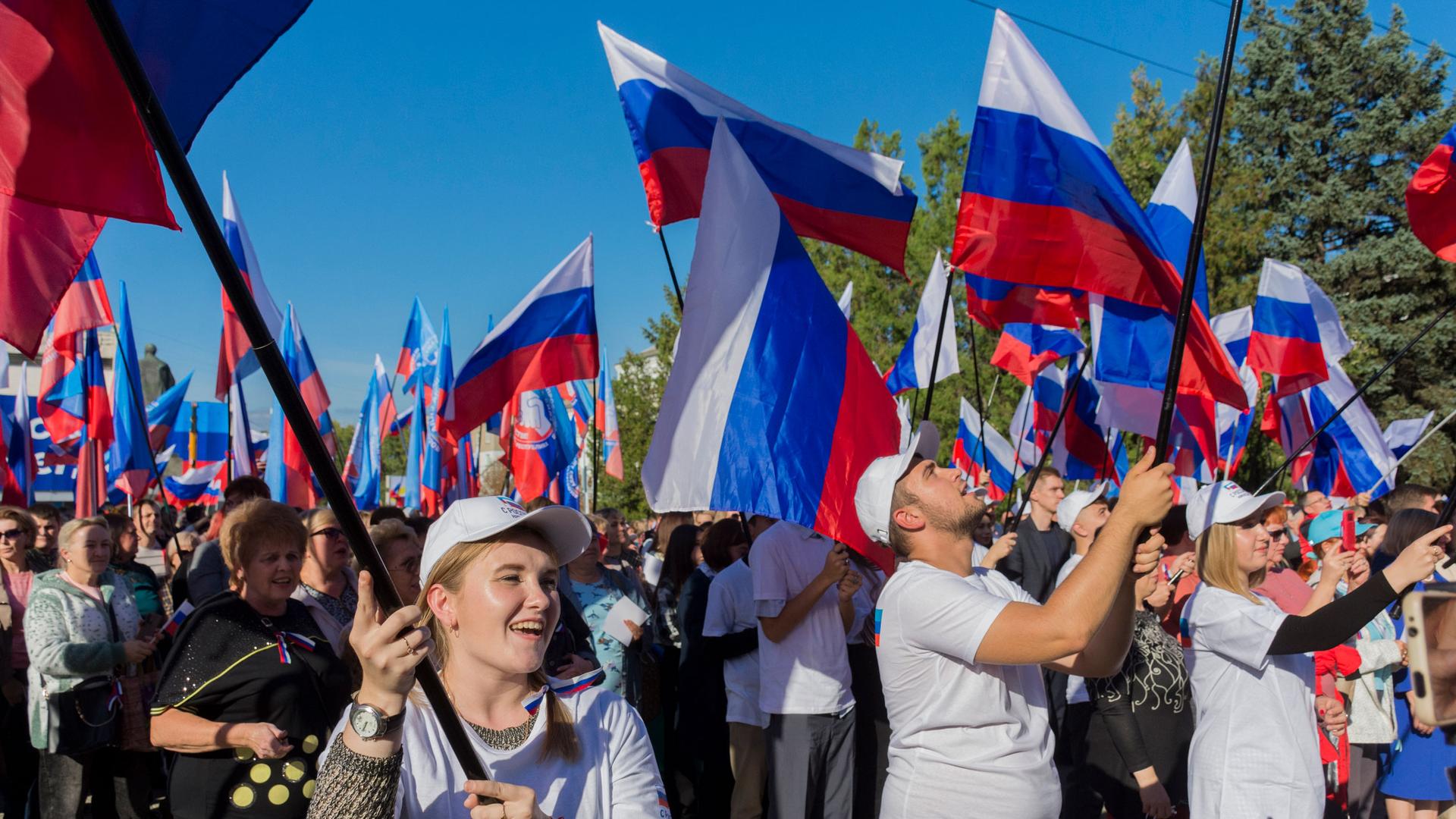 People wave Russian national flags as they gather during celebrations marking the annexation of the Luhansk region into Russia in Luhansk, Ukraine, Friday, Sept. 30, 2022. 
