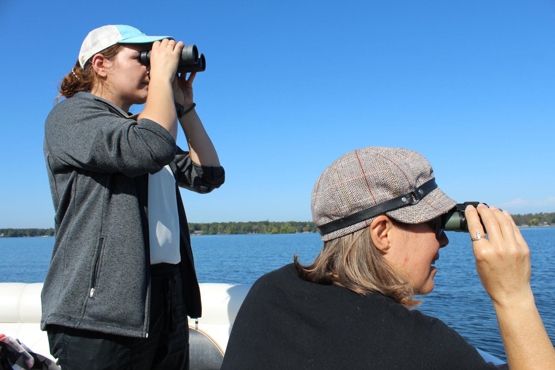 Natasha Bartolotta, communications and outreach coordinator for the National Loon Center (left) and volunteer Jodi Eberhardt (right) search for banded loons on Cross Lake.