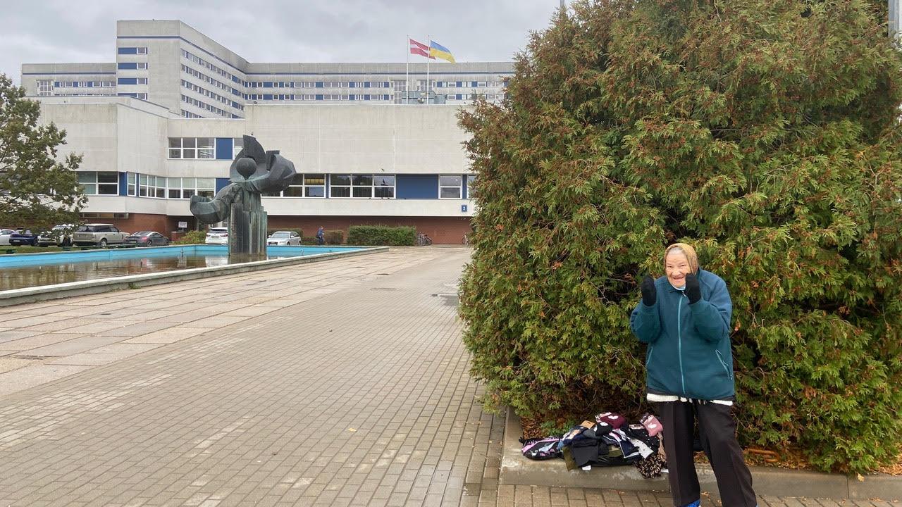 An elderly entrepreneur hawks socks near the entrance to Latvia's largest hospital