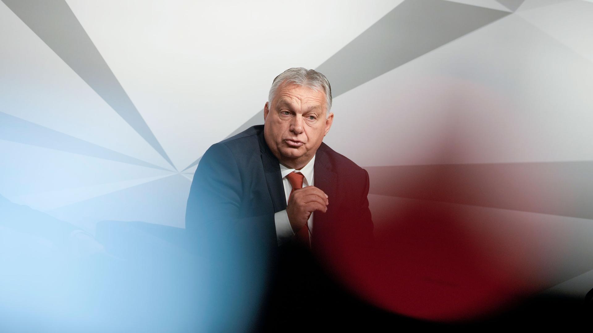 Hungarian Prime Minister Viktor Orban speaks during a panel discussion with a white blurry background. 