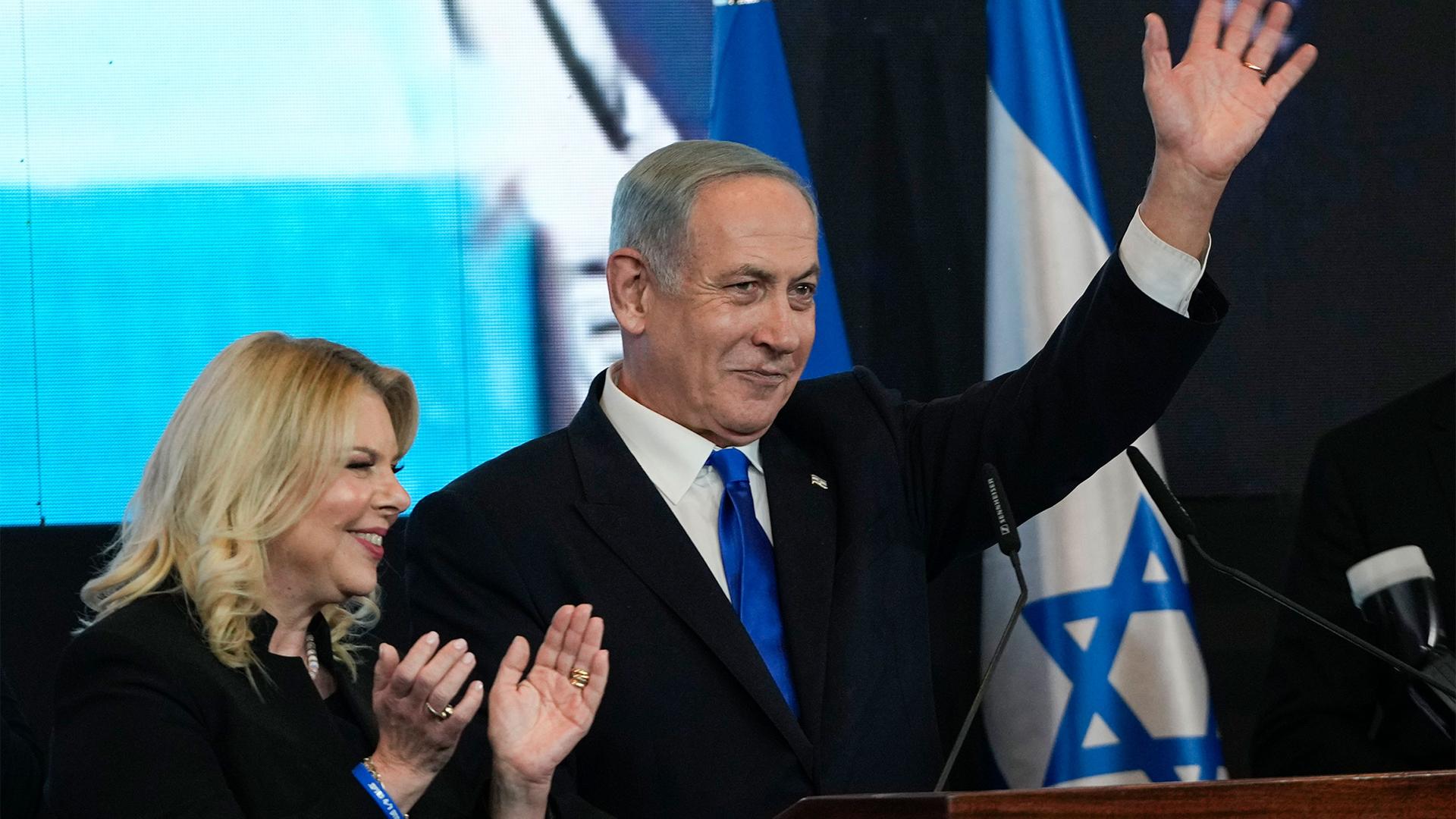 Benjamin Netanyahu, accompanied by his wife Sara, waves to his supporters after first exit poll results for the Israeli Parliamentary election at his party's headquarters in Jerusalem