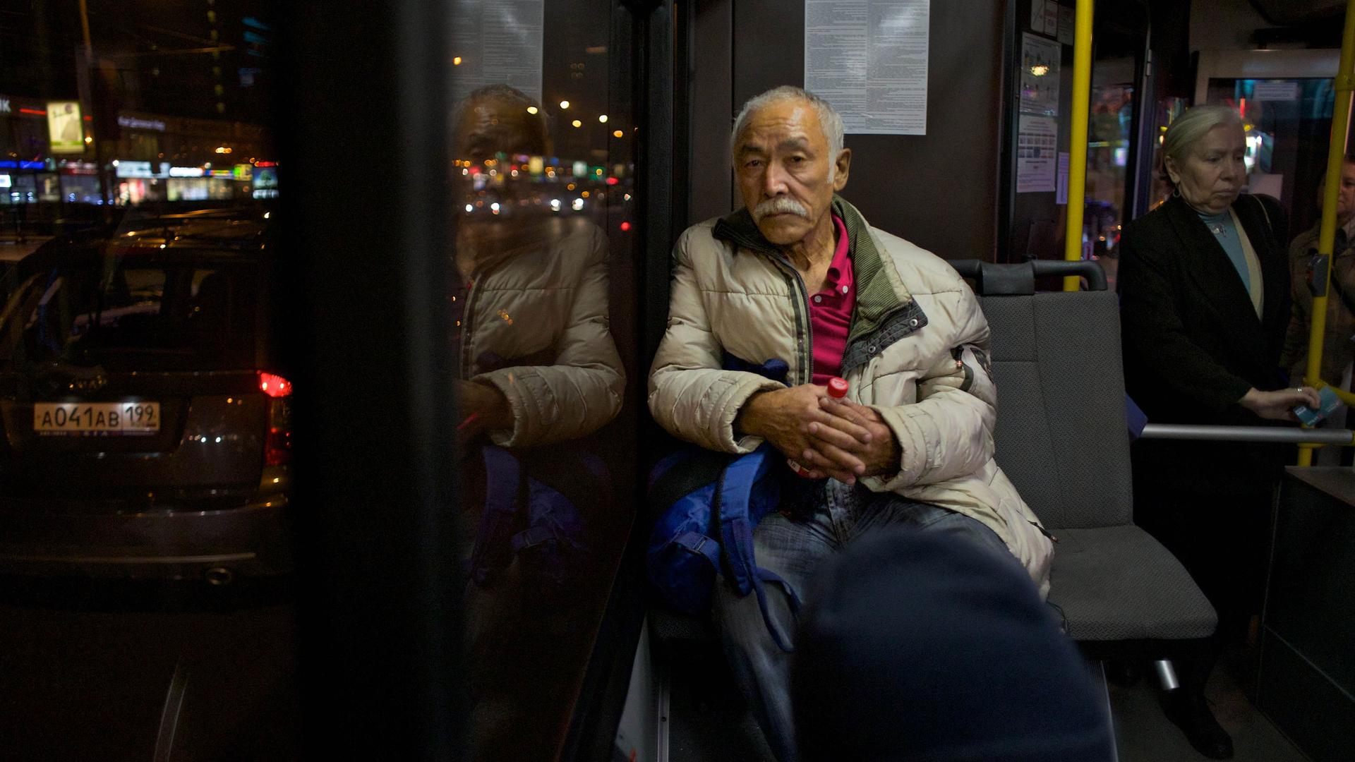 In this photo taken on Tuesday, Sept. 4, 2012, an elderly man sits inside a bus in the station of Moscow, Russia. More and more migrants from the Central Asia are coming come to Moscow in search of work.