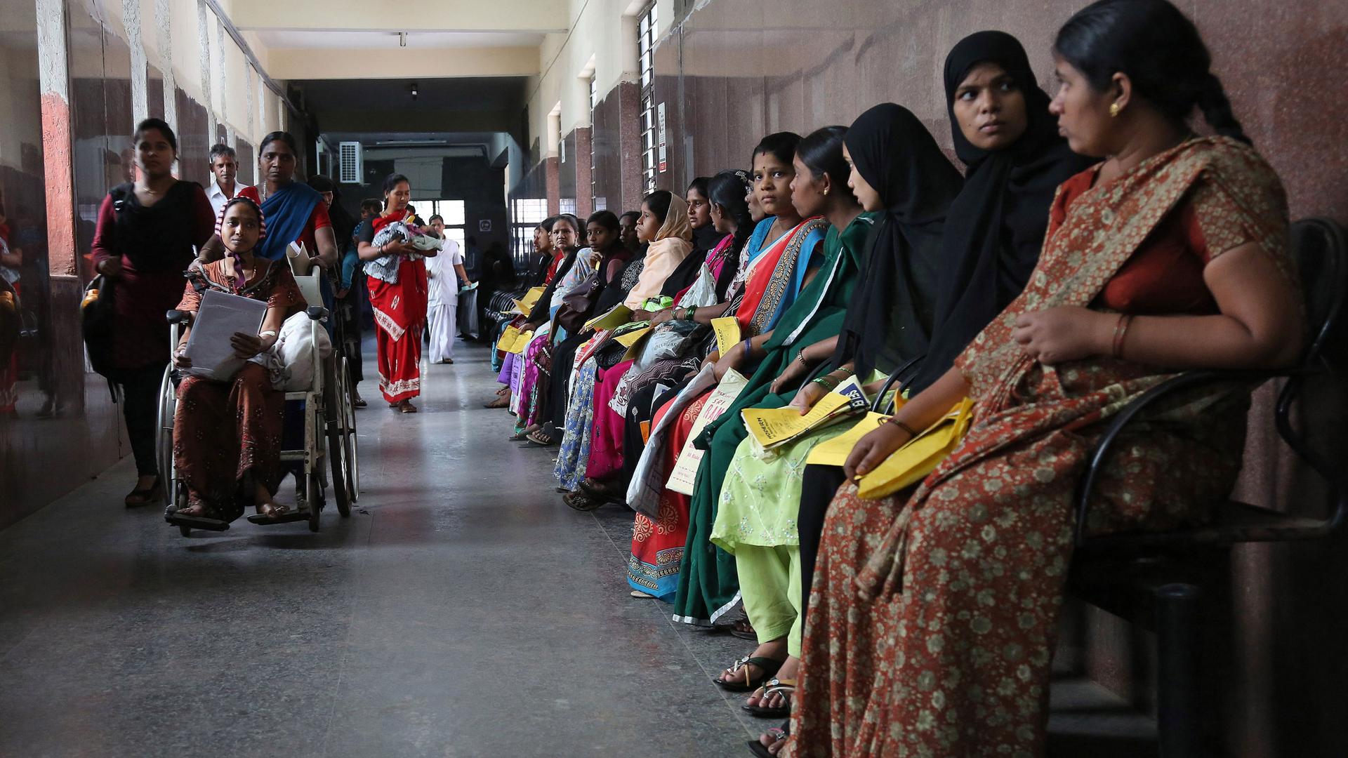 Pregnant women hold their medical cards and wait for their turn to be examined at a government hospital on World Population Day in Hyderabad, India, Friday, July 11, 2014. 