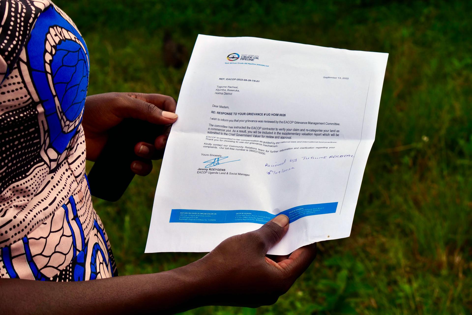 Rachel Tugume shows a letter from EACOP about reevaluating the value of her land.