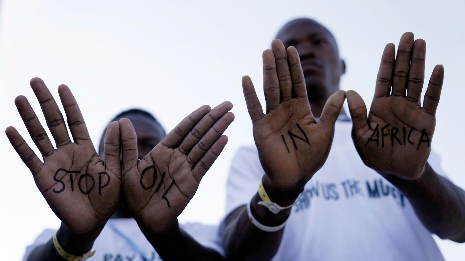 Demonstrators show "stop oil in Africa" written on their hands during a protest with Stop Pipelines coalition against pipelines in East Africa.