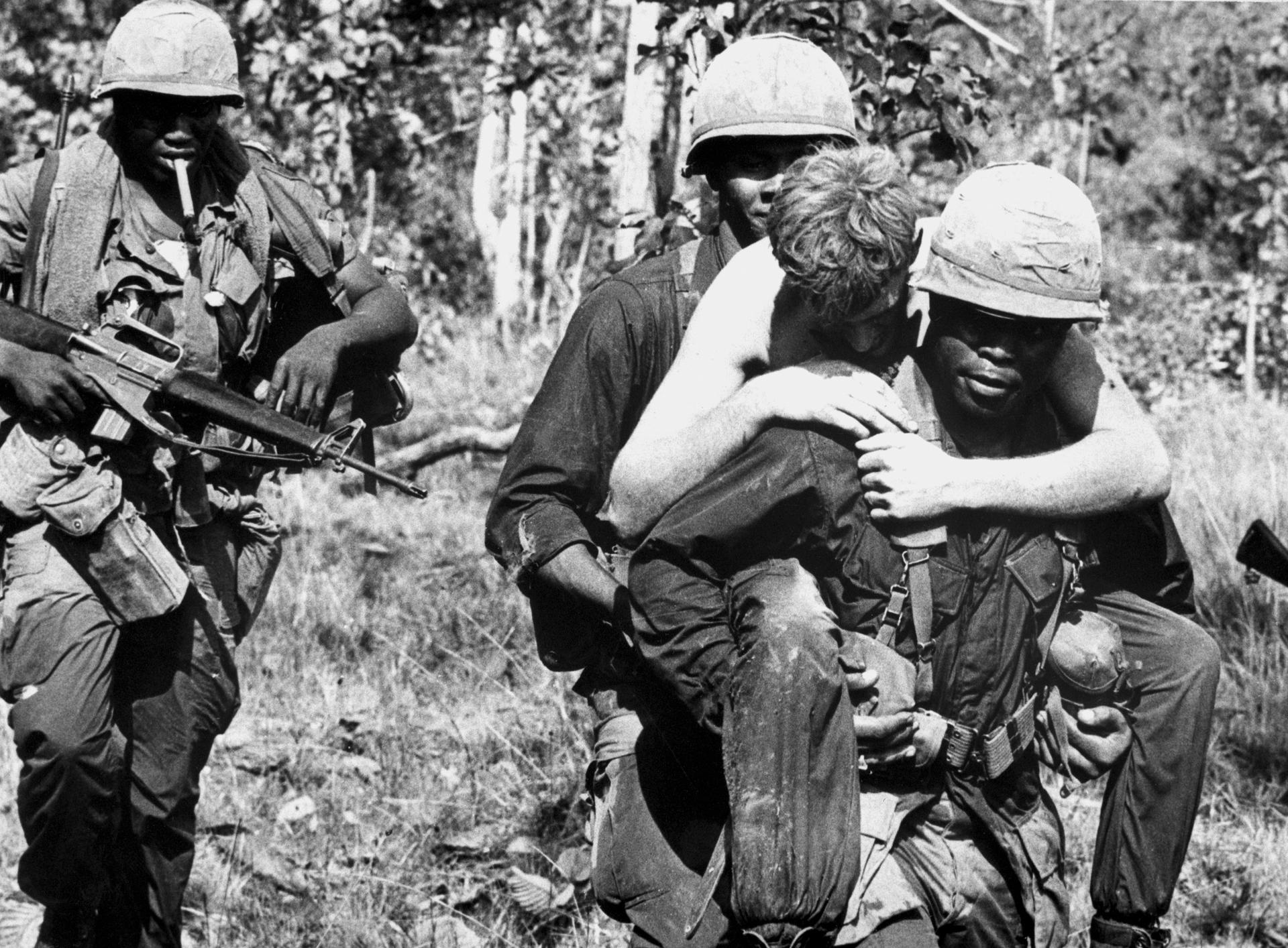 A wounded soldier is carried by members of the 1st Cavalry Division near the Cambodian border during the Vietnam War.