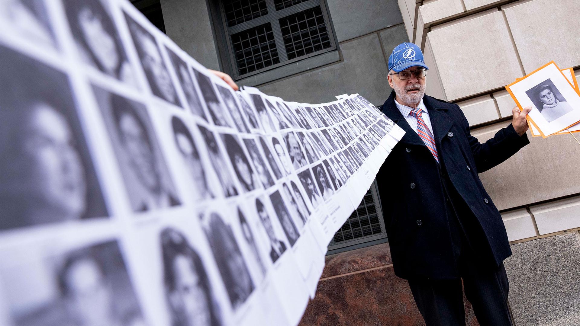 Paul Hudson of Sarasota, Fla., holds up a photo of his daughter Melina who was killed at 16 years old, along with the photos of almost a hundred other victims of the bombing of Pan Am Flight 103