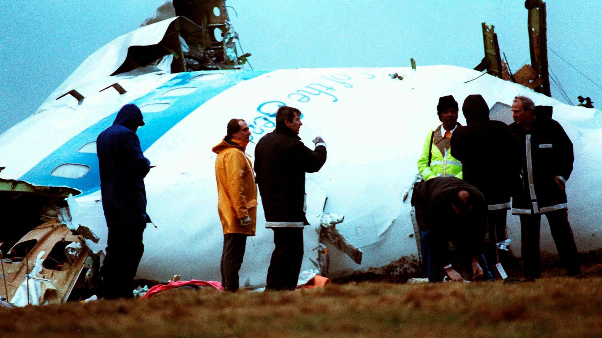 Unidentified crash investigators inspect the nose section of the crashed Pan Am flight 103 in a field near Lockerbie, Scotland, Dec. 23, 1988.