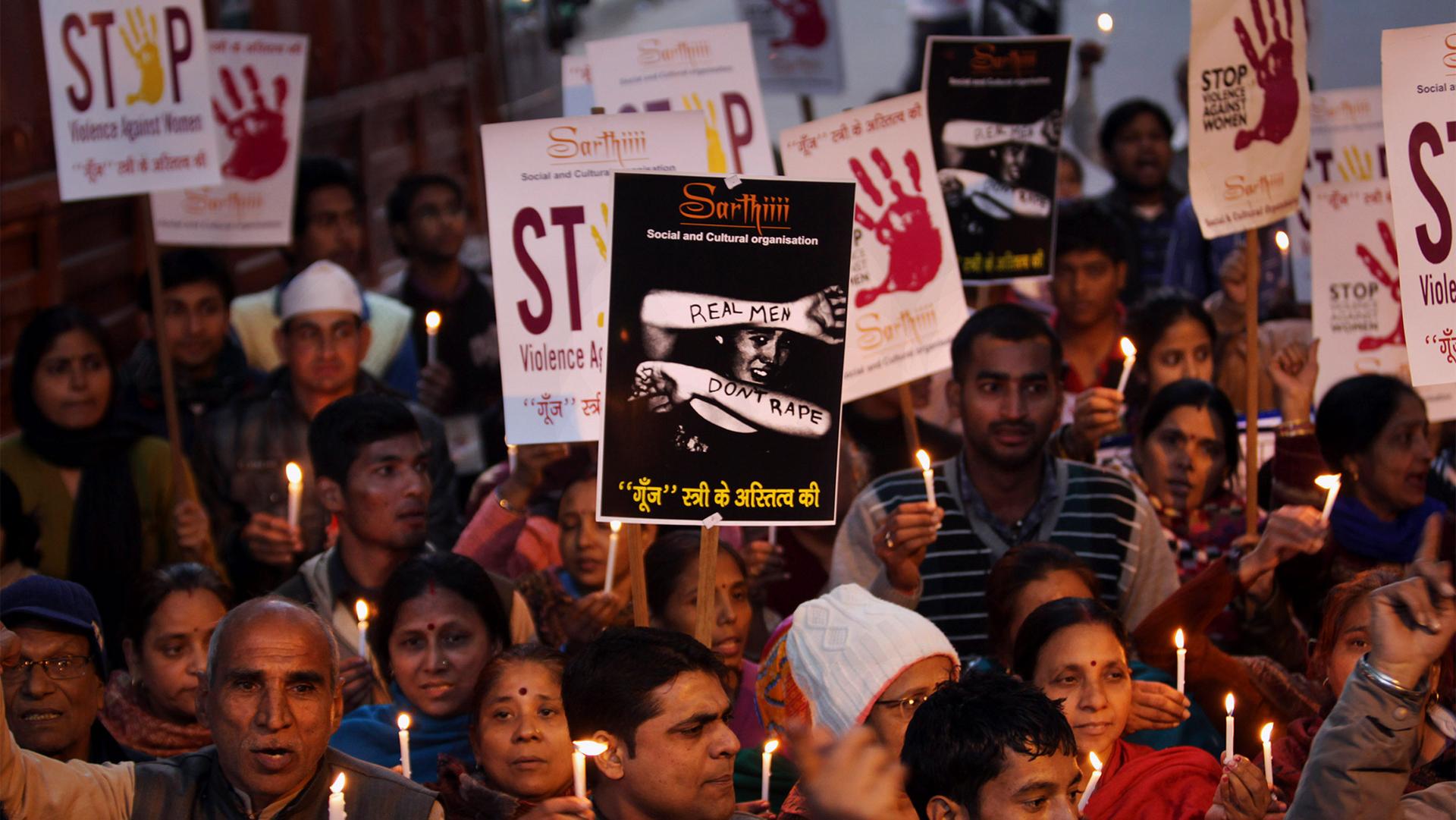 Indian people hold placards and candles as they participate at a candle light vigil as they mark the first anniversary of a young woman's demise after the fatal gang rape, in New Delhi, India, Dec. 29, 2013.
