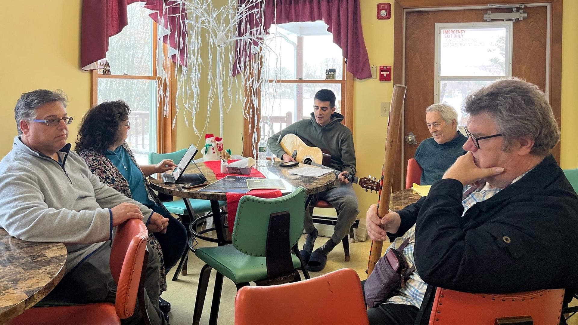 Joseph Arana Sanchez (center) rehearses on his guitar ahead of a benefit concert for fellow Ukrainians living in Vermont.