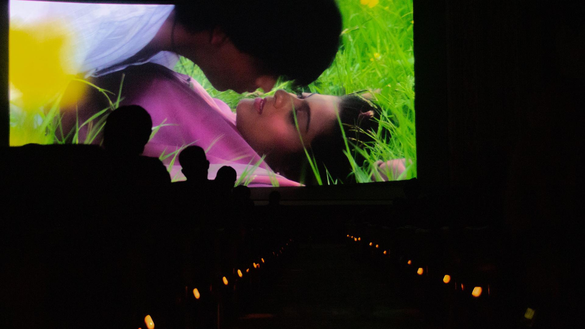 An audience watches actors Shah Rukh Khan and Kajol on the big screen.