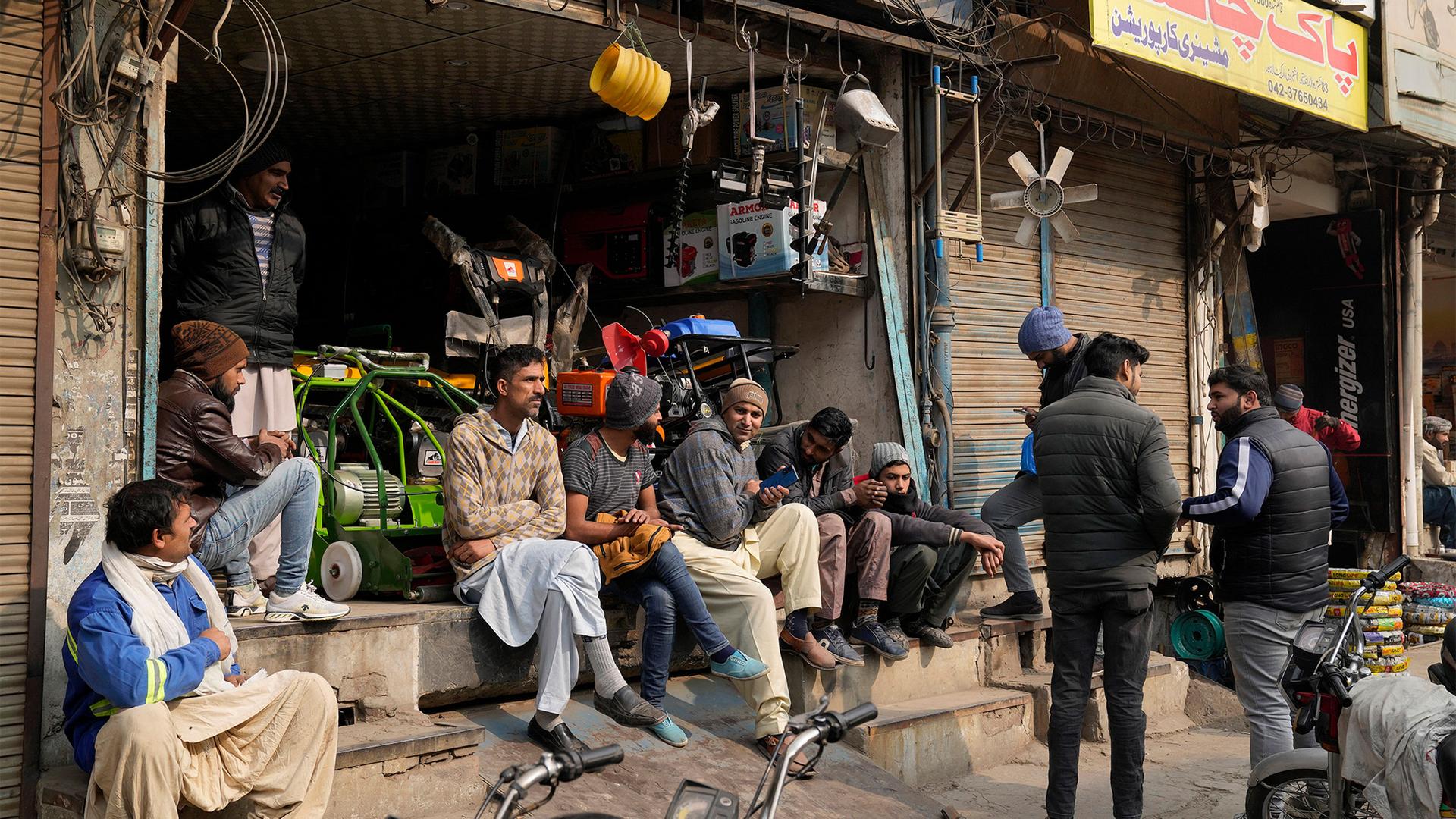 Shopkeepers and workers wait for electric power at a market following a power breakdown across the country, in Lahore, Pakistan, Jan. 23, 2023.