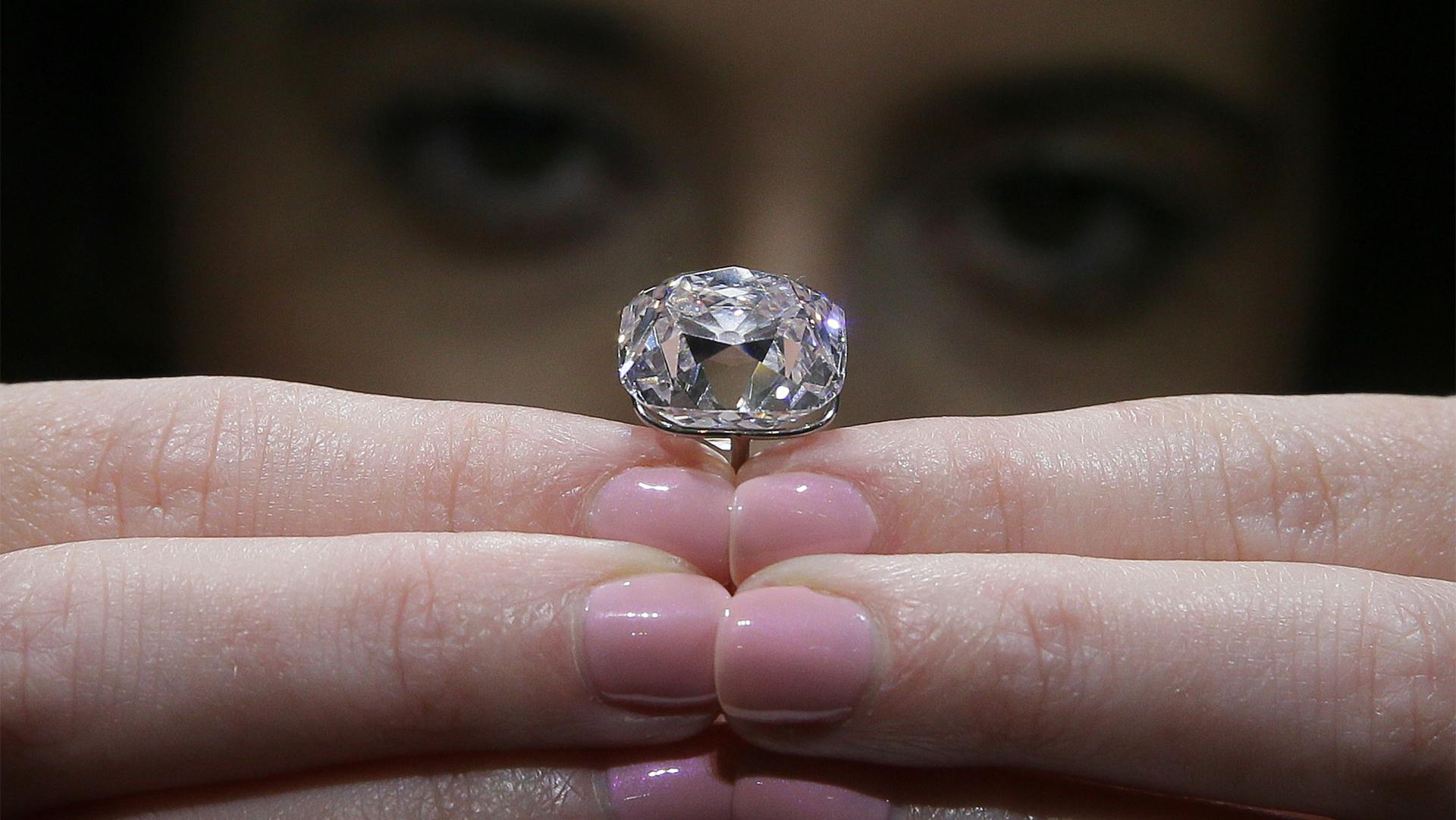 A member of auction house staff poses for a picture with a 19-carat pink diamond at Christie's auction house, in London, Oct. 18, 2017. 