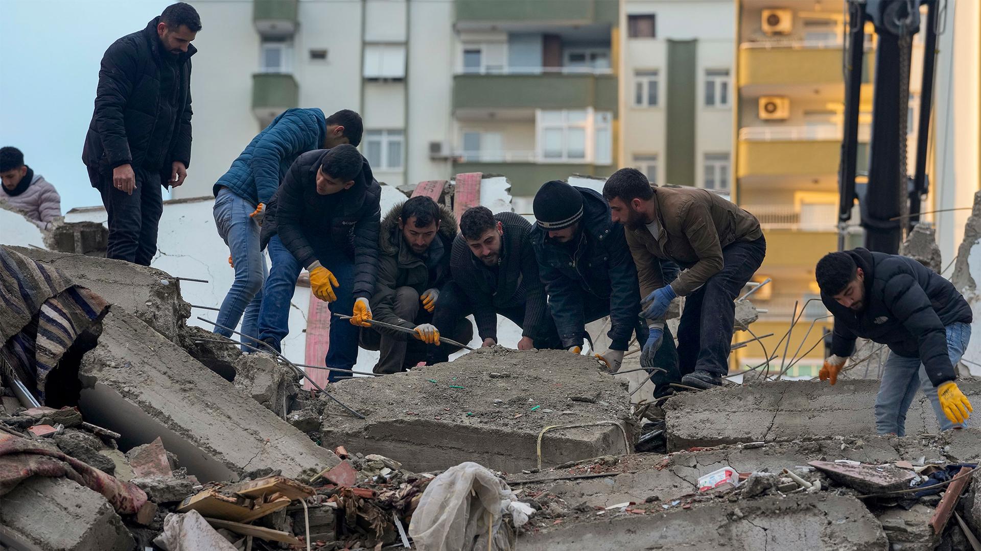 Men remove debris as they search for people in a destroyed building in Adana, Turkey, Feb. 6, 2023.
