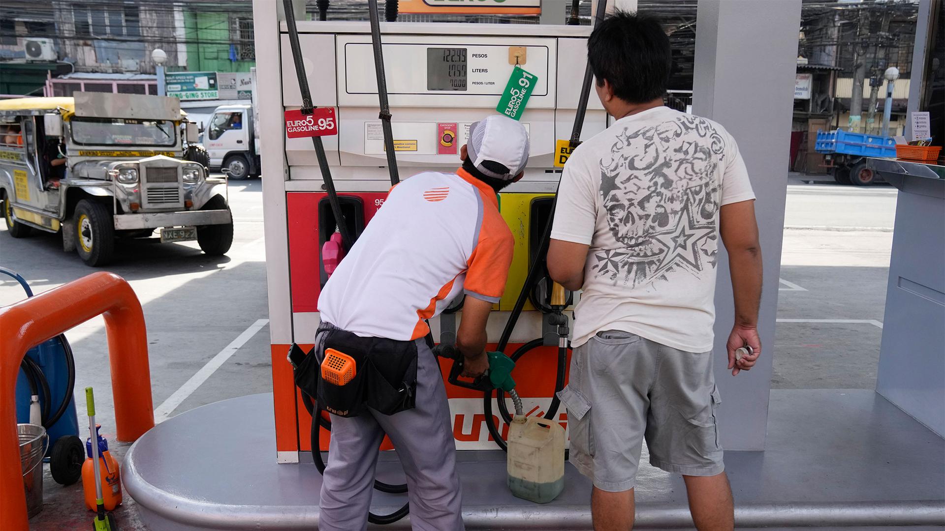 A worker fills up a plastic container with gasoline at a gas station in Pasay, Philippines, Oct. 11, 2022.