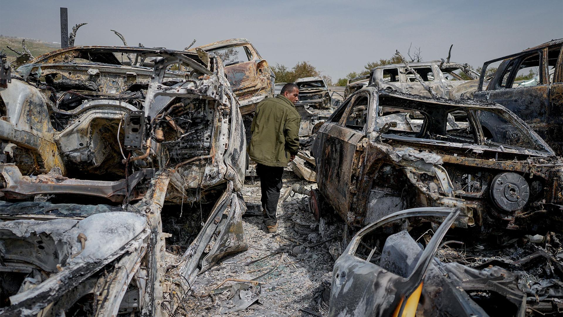 A Palestinian man walks between scorched cars in a scrapyard, in the town of Hawara, near the West Bank city of Nablus, Feb. 27, 2023.