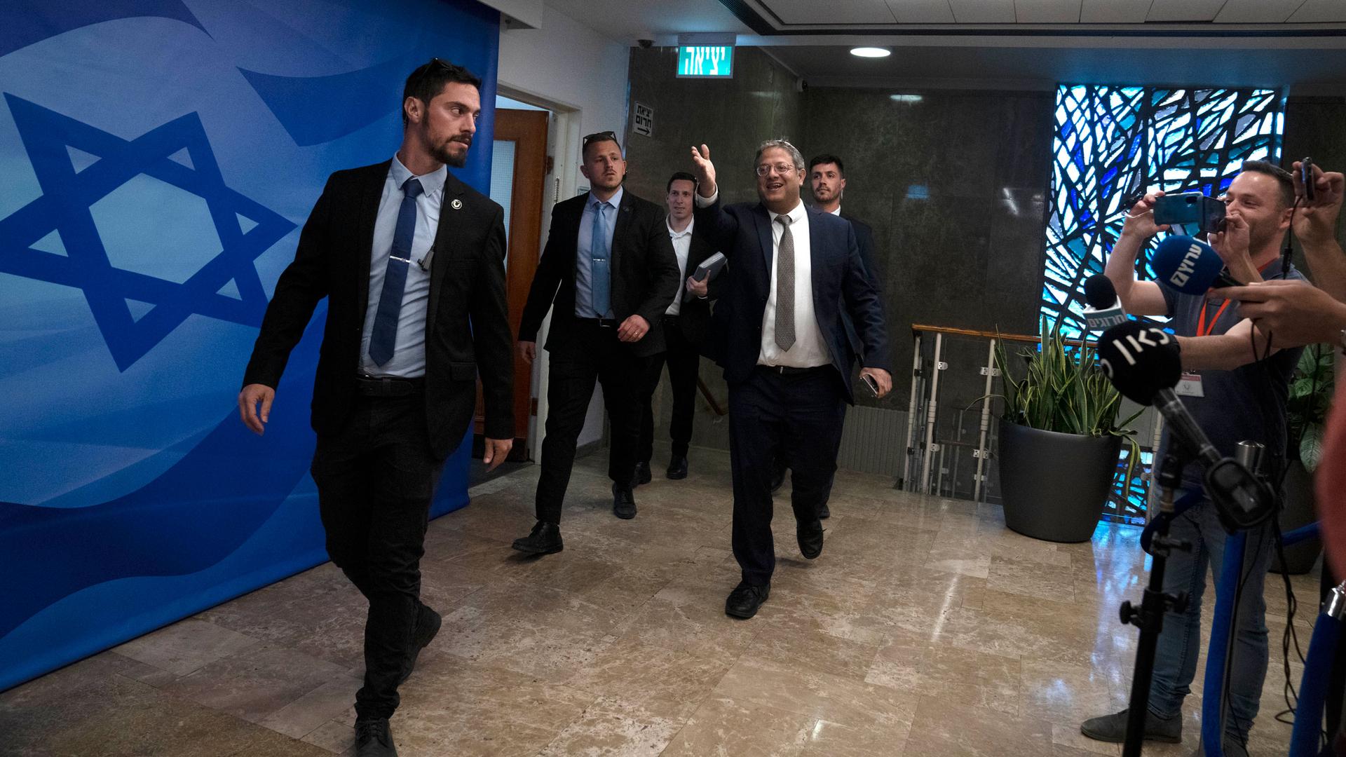 Israel's Minister of National Security Itamar Ben-Gvir, flanked by his security detail, gestures as he hurries to the weekly cabinet meeting in Jerusalem, Sunday, March 12, 2023.