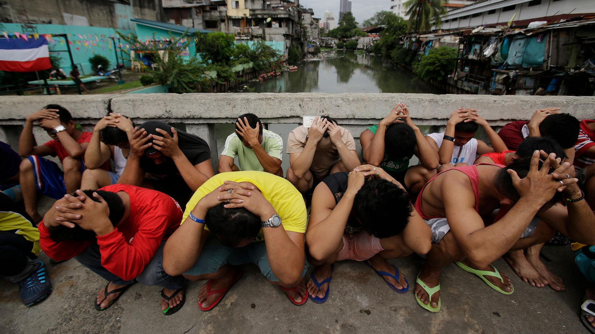 Men place their hands over their heads as they are rounded up during a continuing "war on drugs" police campaign of Philippine President Rodrigo Duterte in Manila, Philippines, Oct. 7, 2016. 