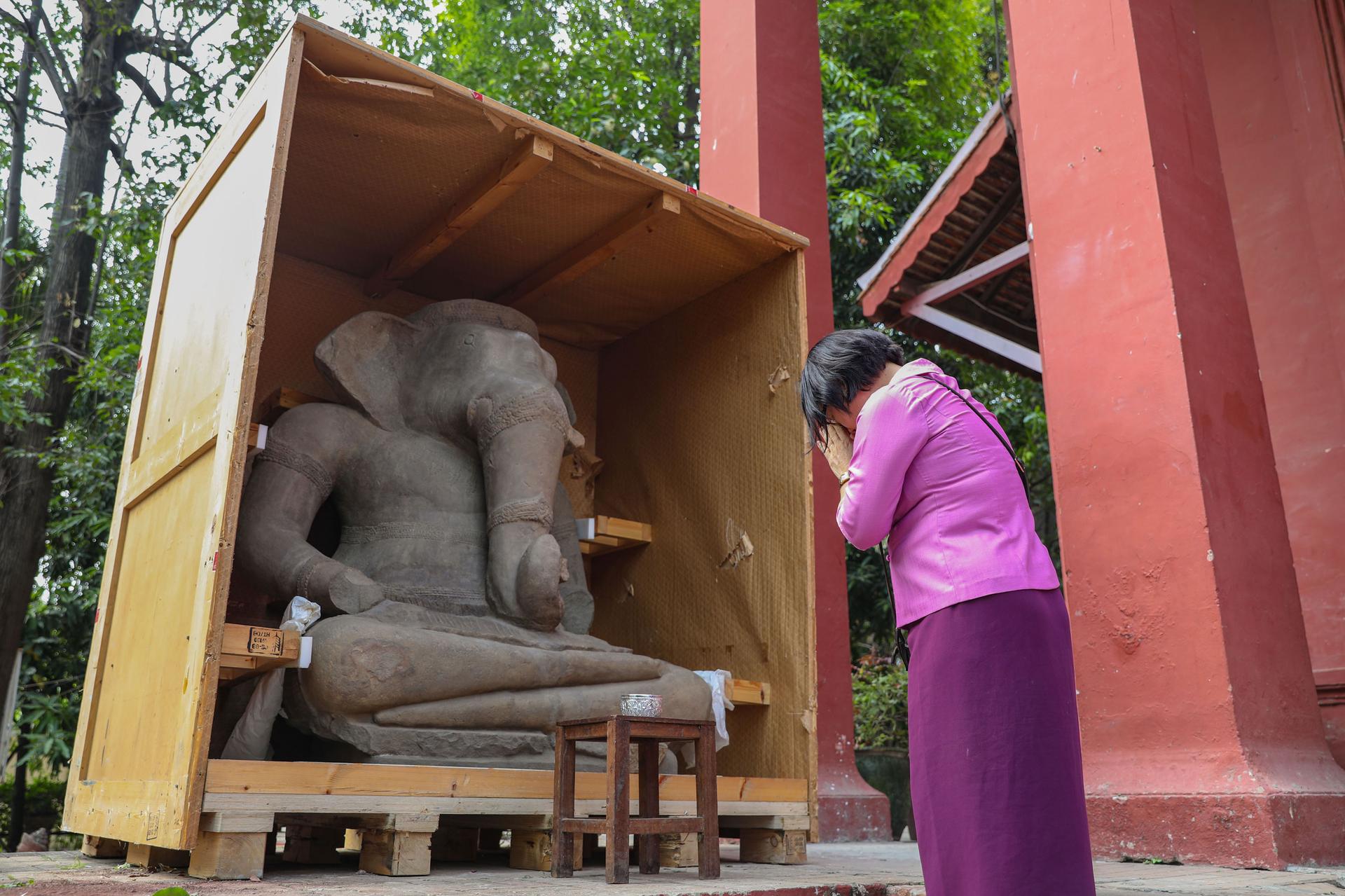 Ros Sarou, an official with the Ministry of Culture and Fine Arts, whispers a prayer after giving an offering to a recently returned, nearly 4-ton statue of Ganesh that was opened for the first time in 20 years on March 11, 2023.