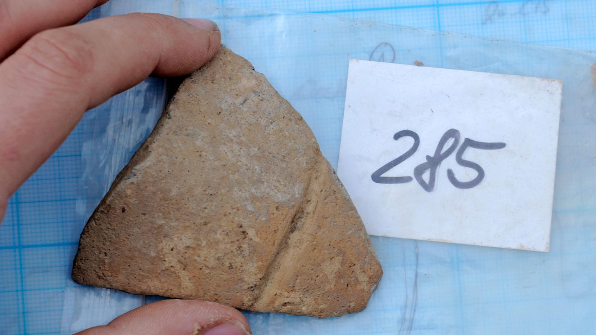 A student shows a piece of ceramic in the archaeological excavation near Salbitz, central Germany, on Friday, April 8, 2011.